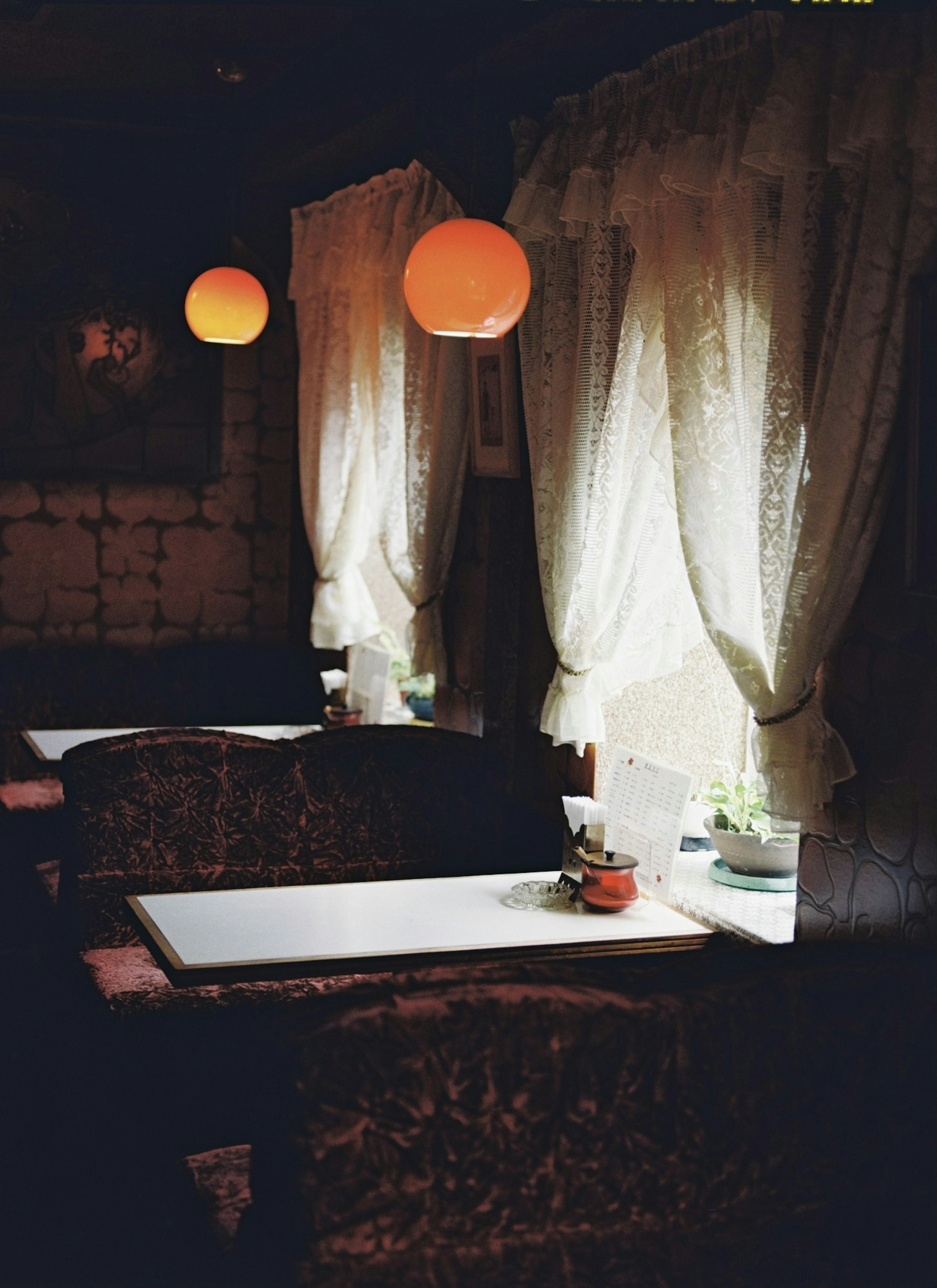 Dimly lit room with white curtains and orange lamps on tables