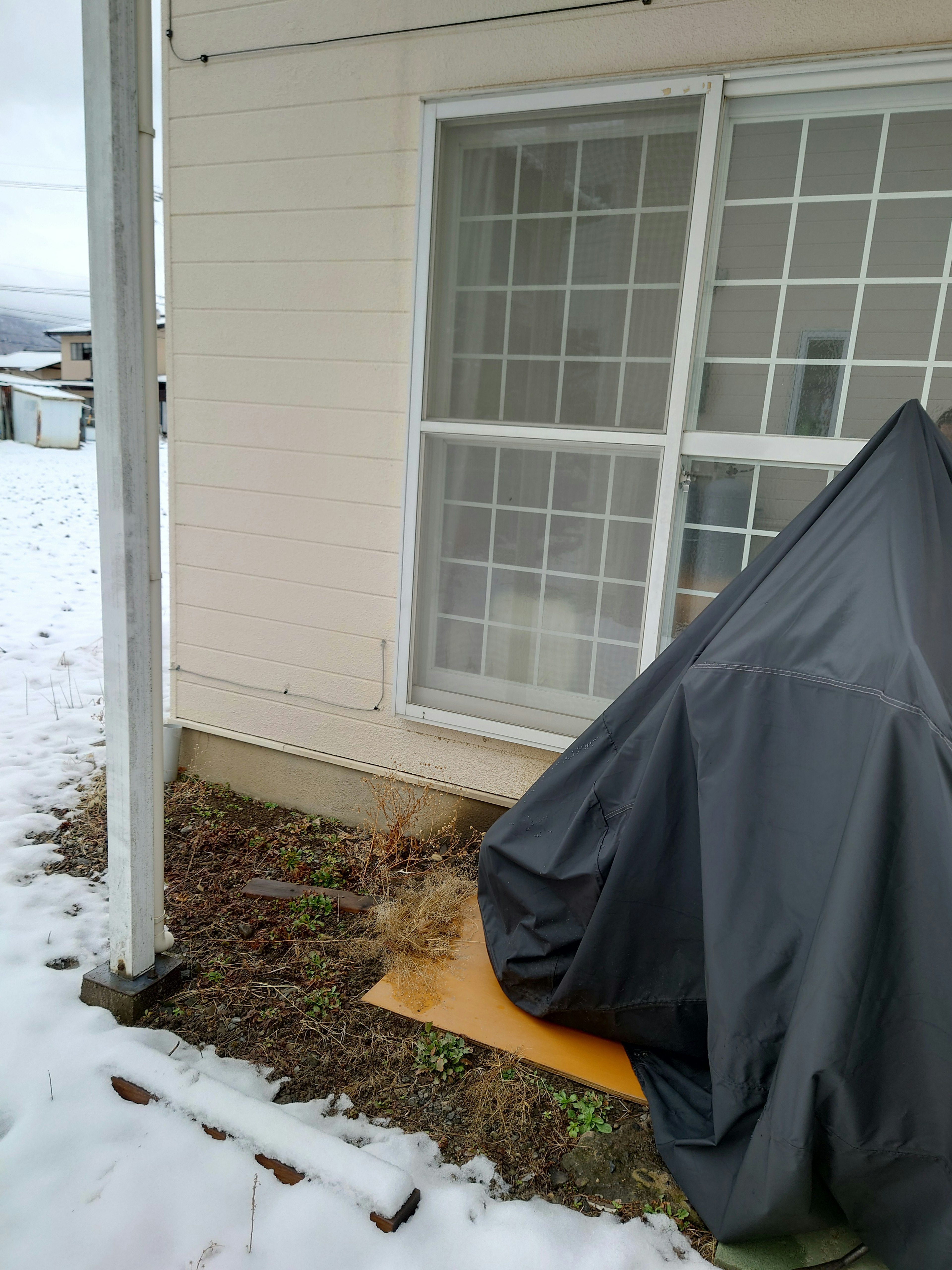 Black covered tent next to a house in the snow