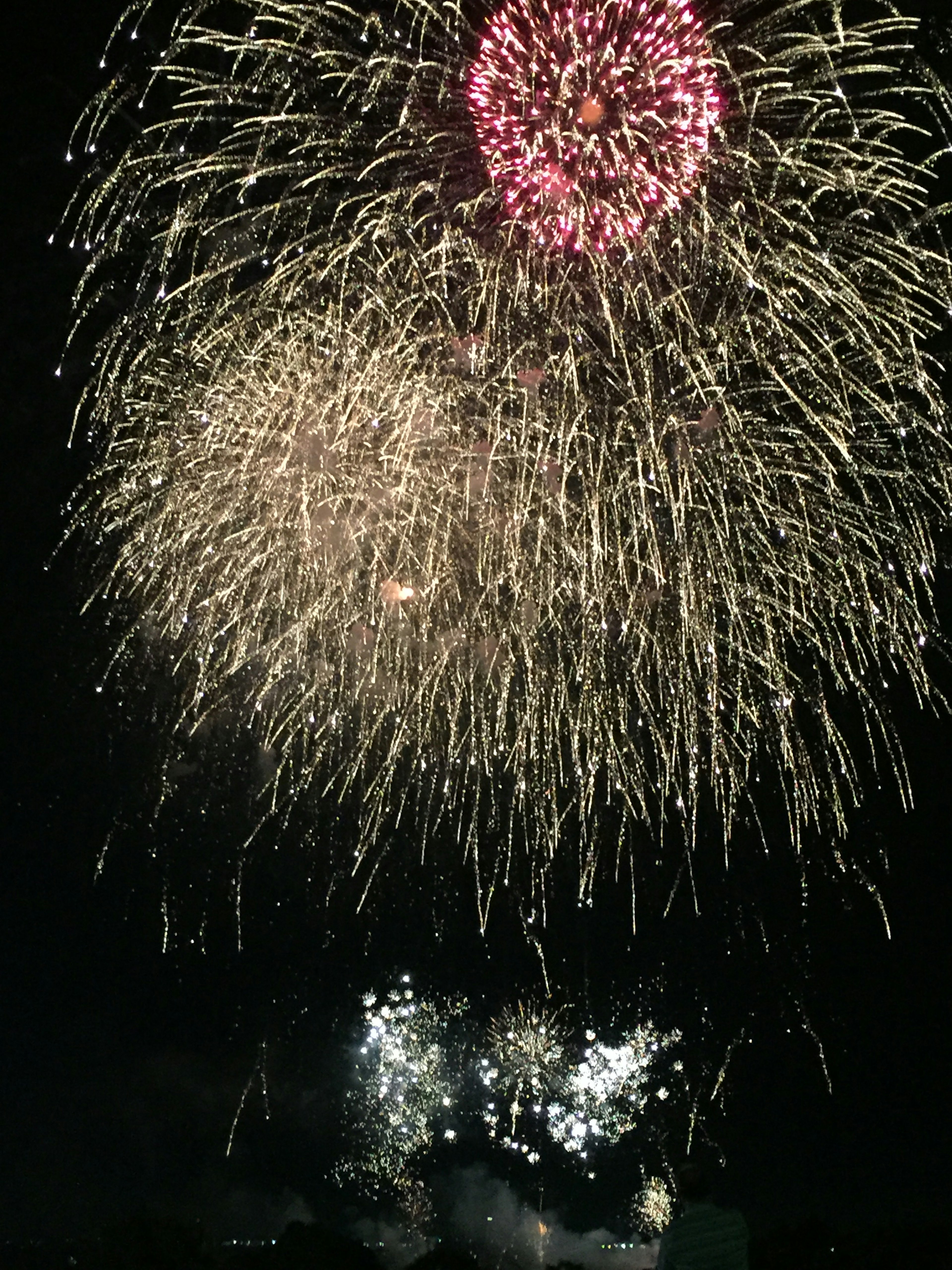 Spettacolo di fuochi d'artificio nel cielo notturno con esplosioni rosse e bianche vivaci