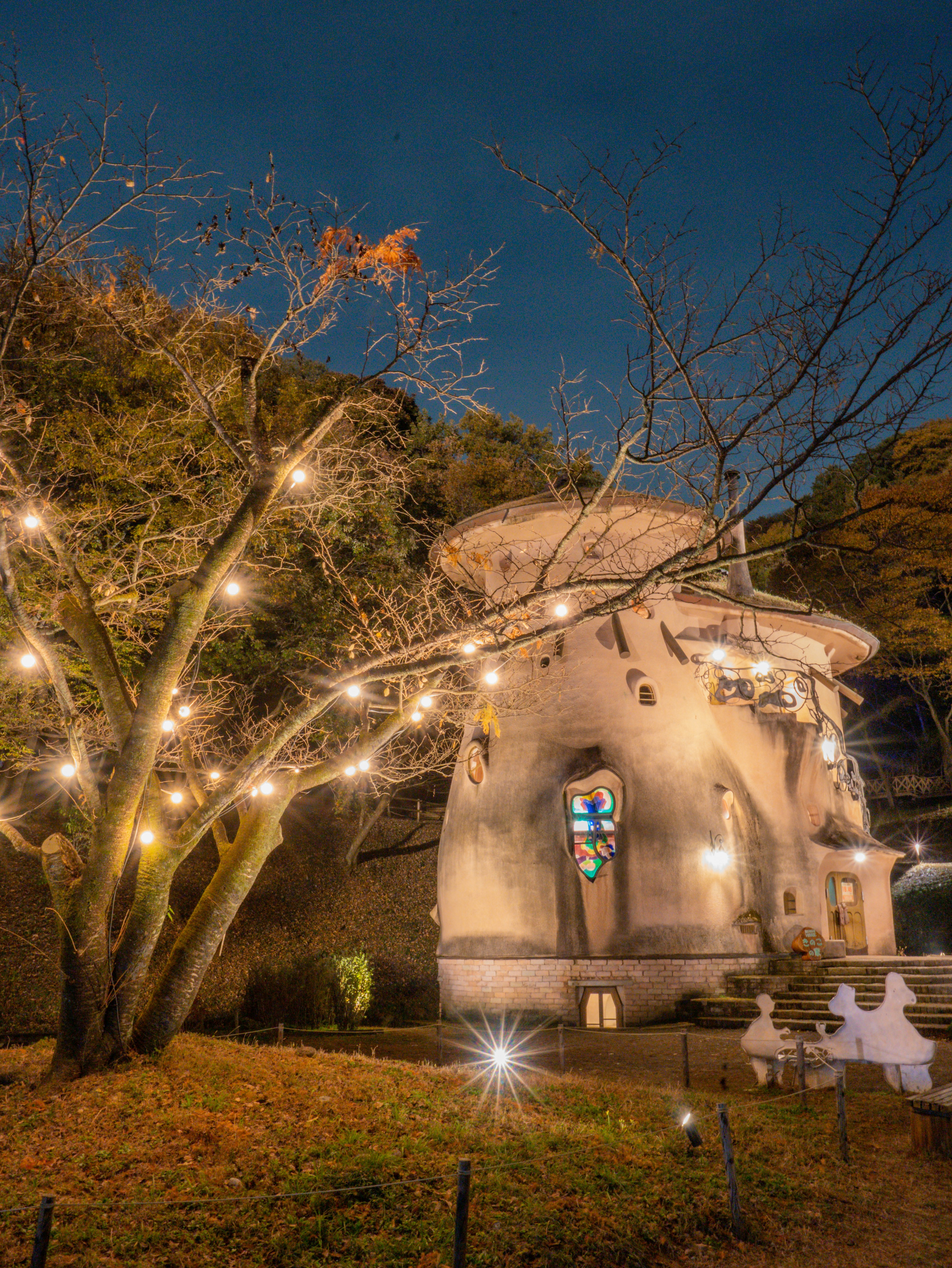 Ein fantasievolles Haus, das nachts mit einem leuchtenden Baum beleuchtet ist