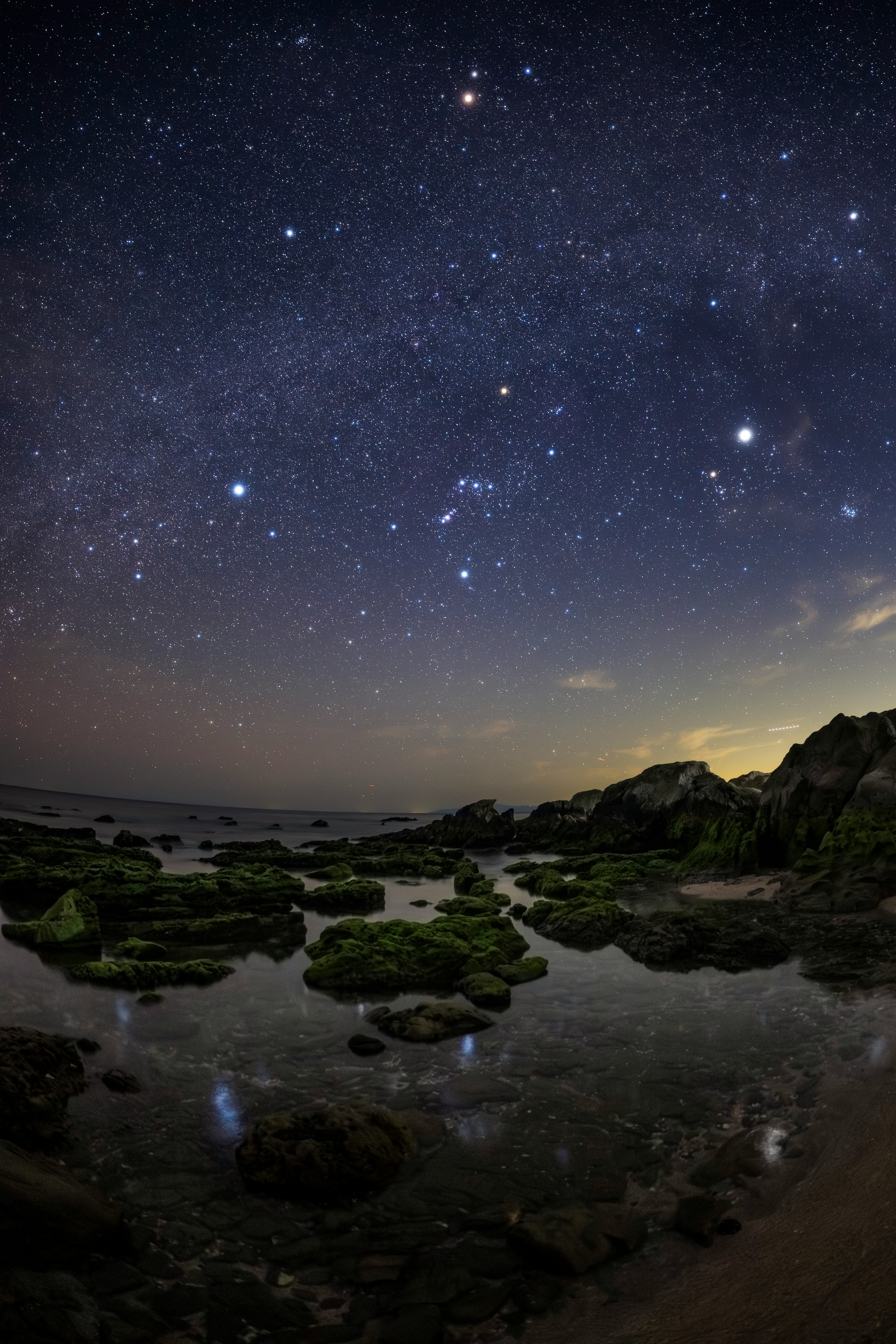 星空映襯下的岩石海岸和水中的倒影