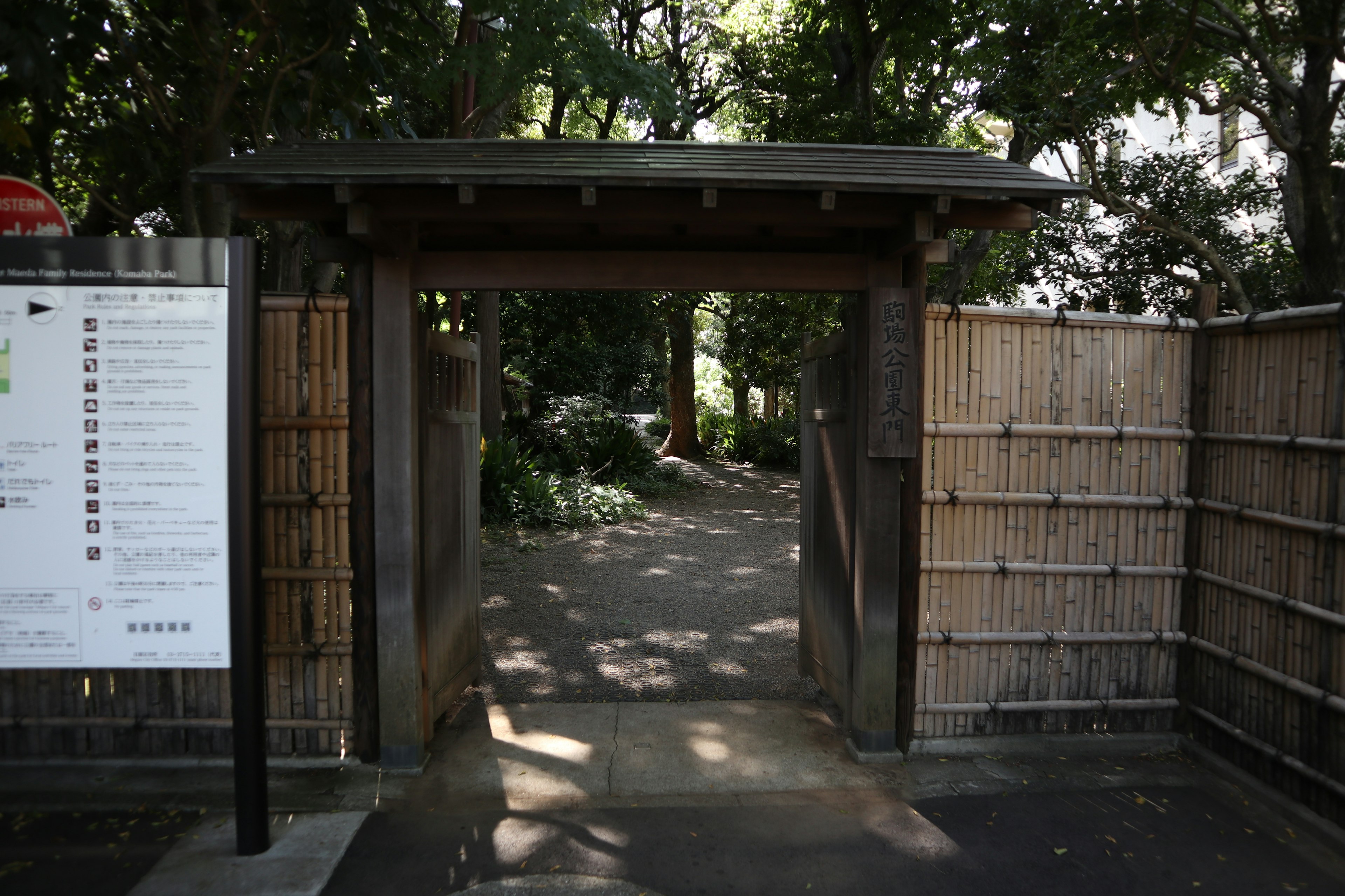 Wooden gate surrounded by greenery with a bamboo fence