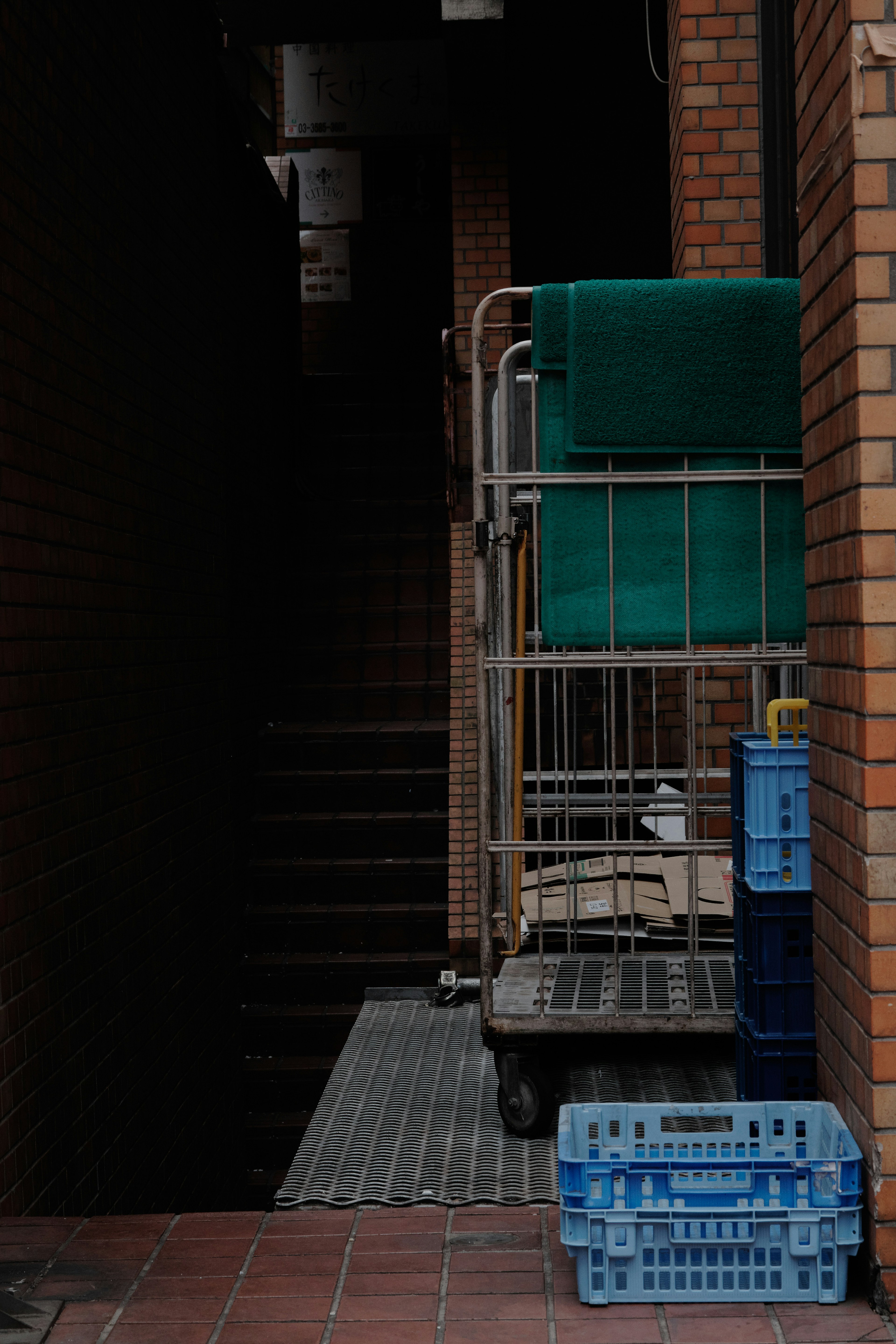 Callejón estrecho con un carrito que tiene toallas verdes y una cesta de plástico azul