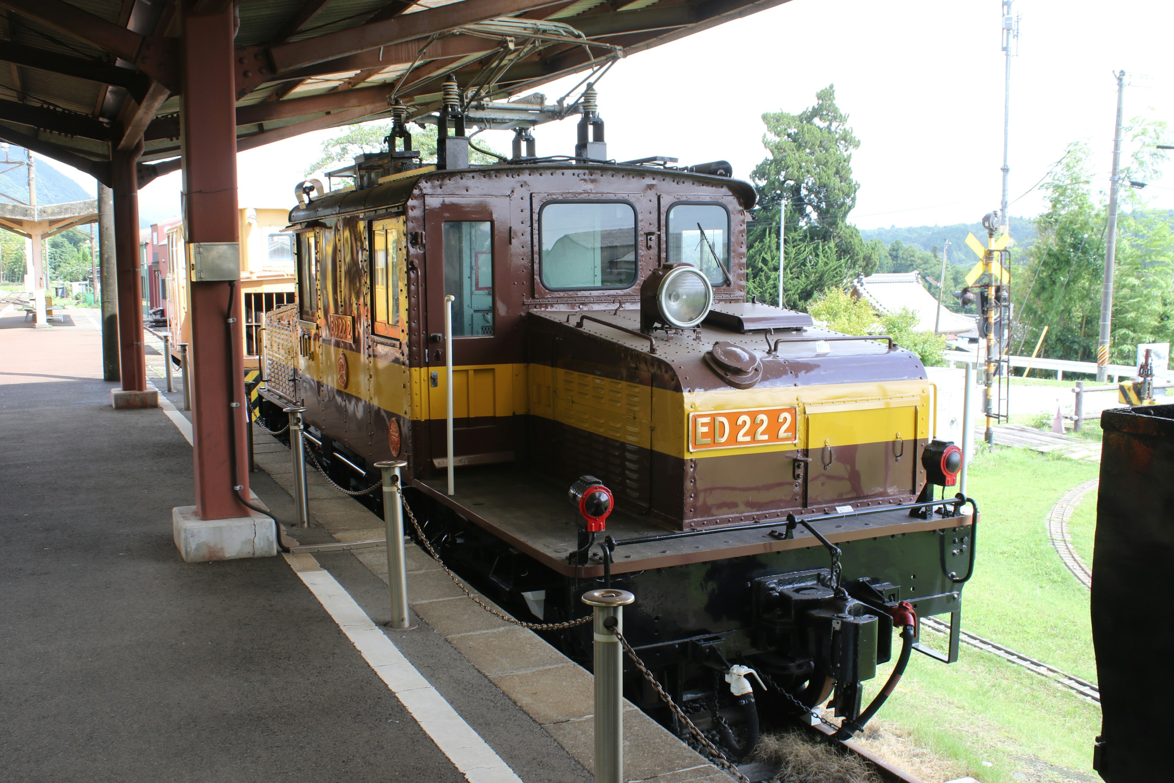 Brown and yellow electric locomotive parked at a train station platform