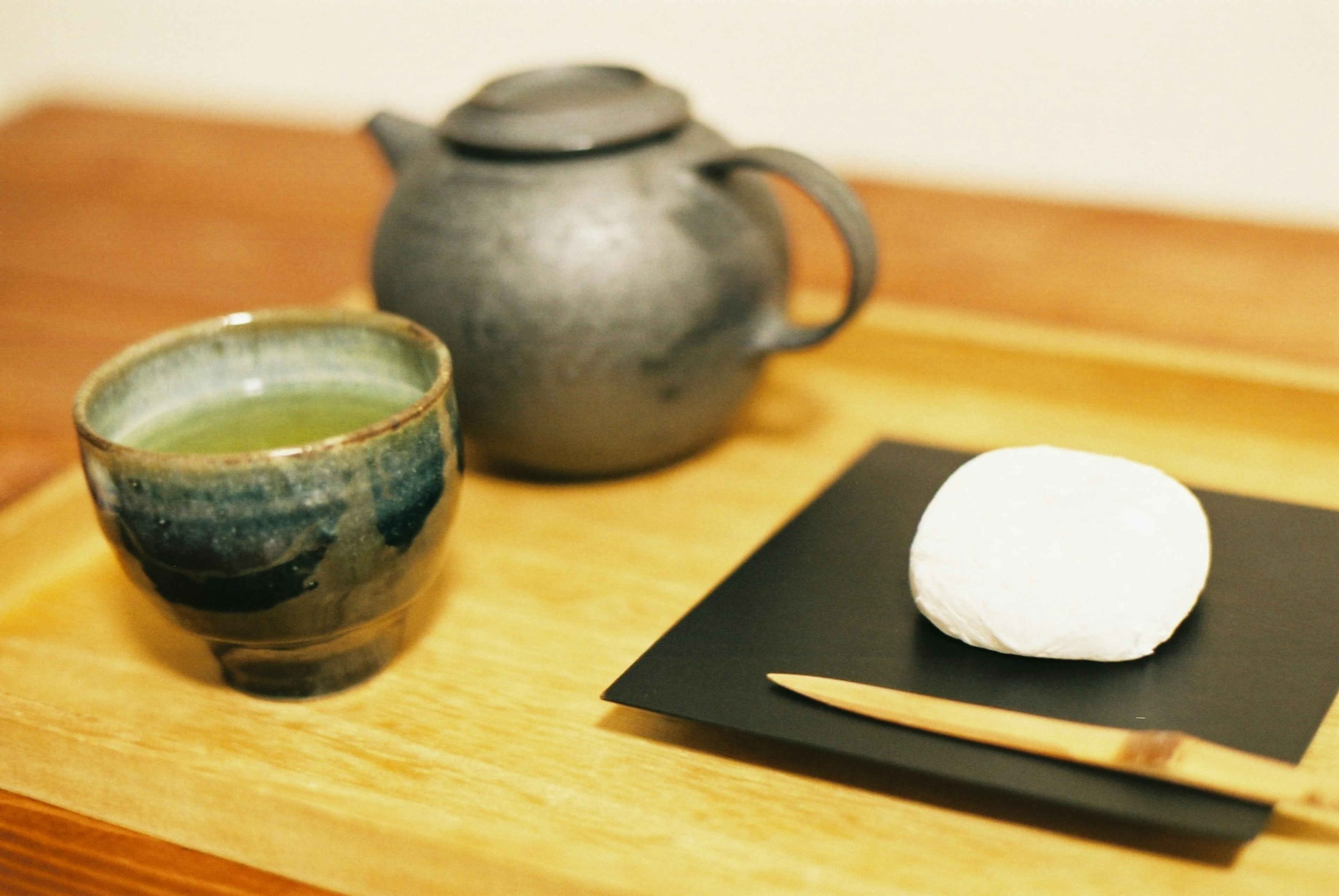 Imagen de una bandeja de madera con té verde y un dulce japonés