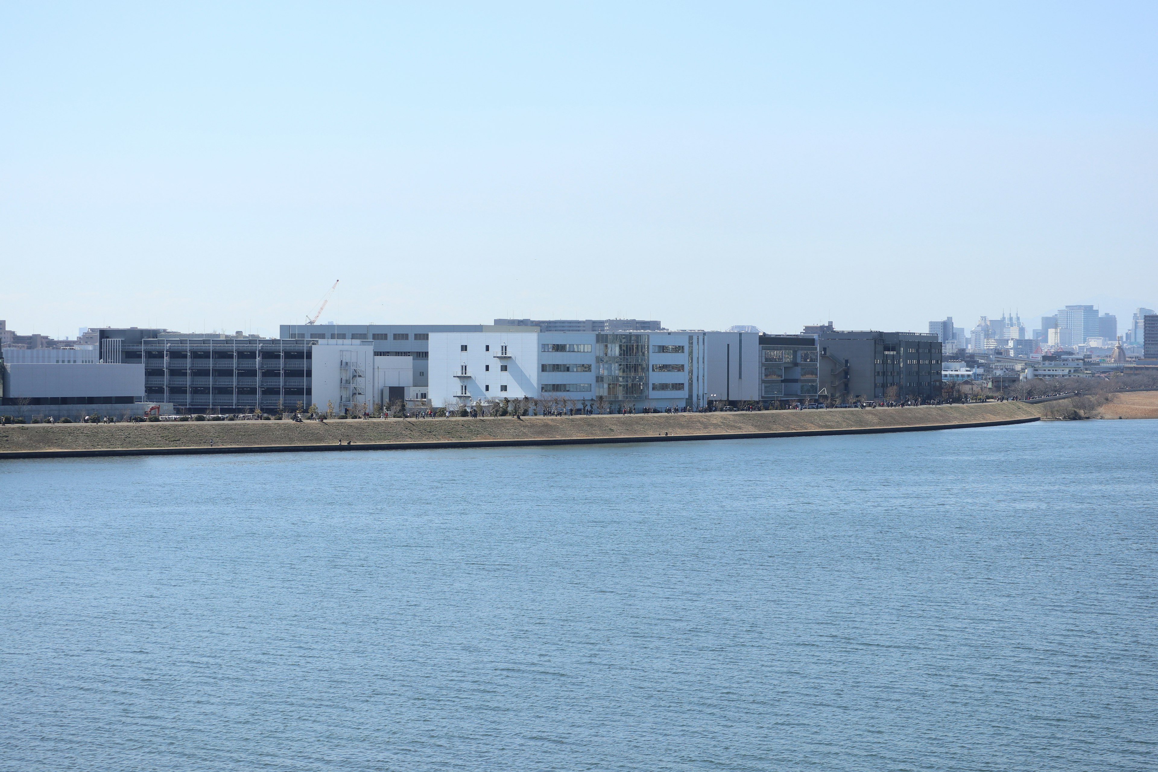 Modern buildings along the riverbank with a clear blue sky