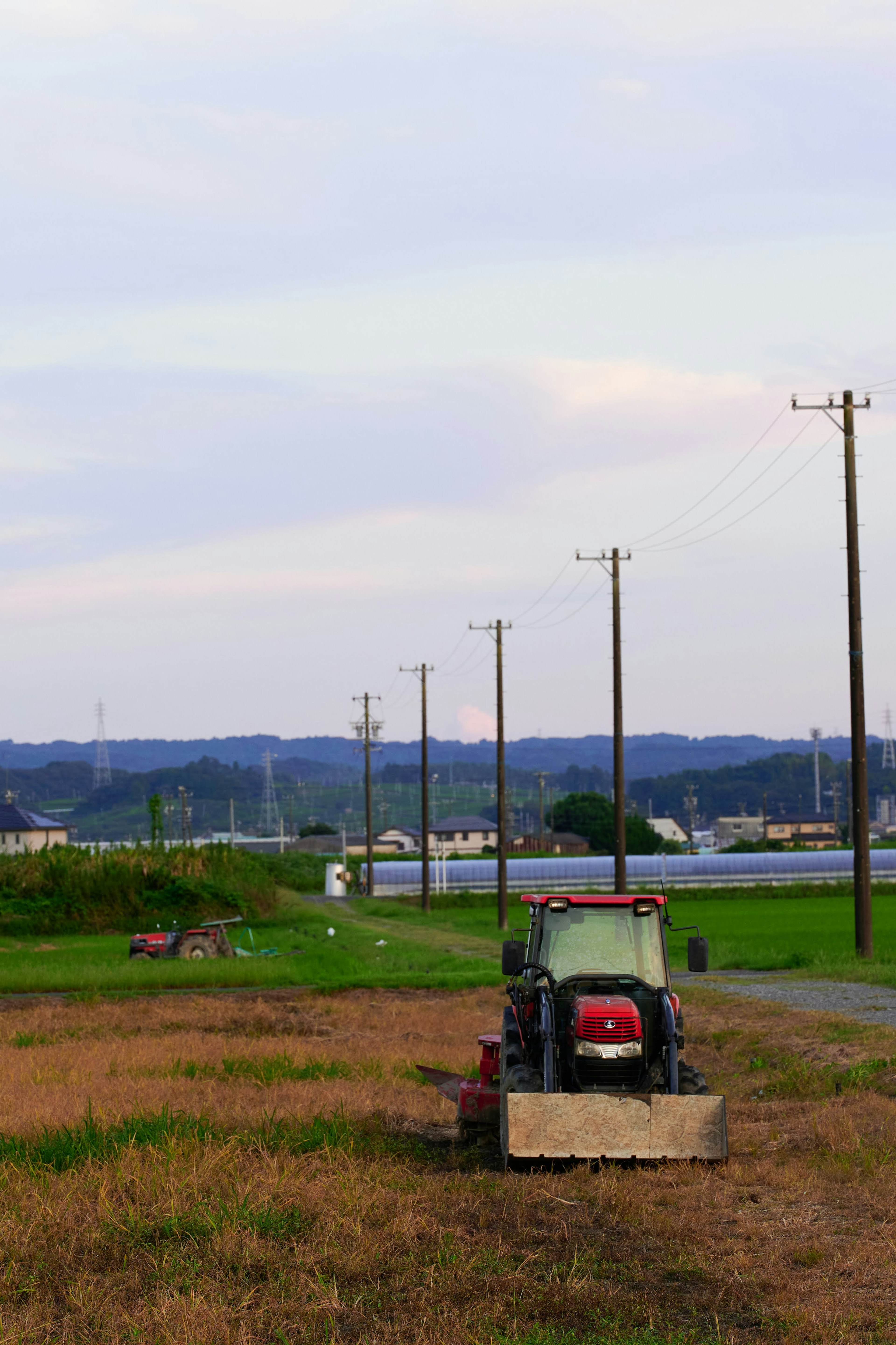 Un paysage rural avec un tracteur et des poteaux électriques alignés