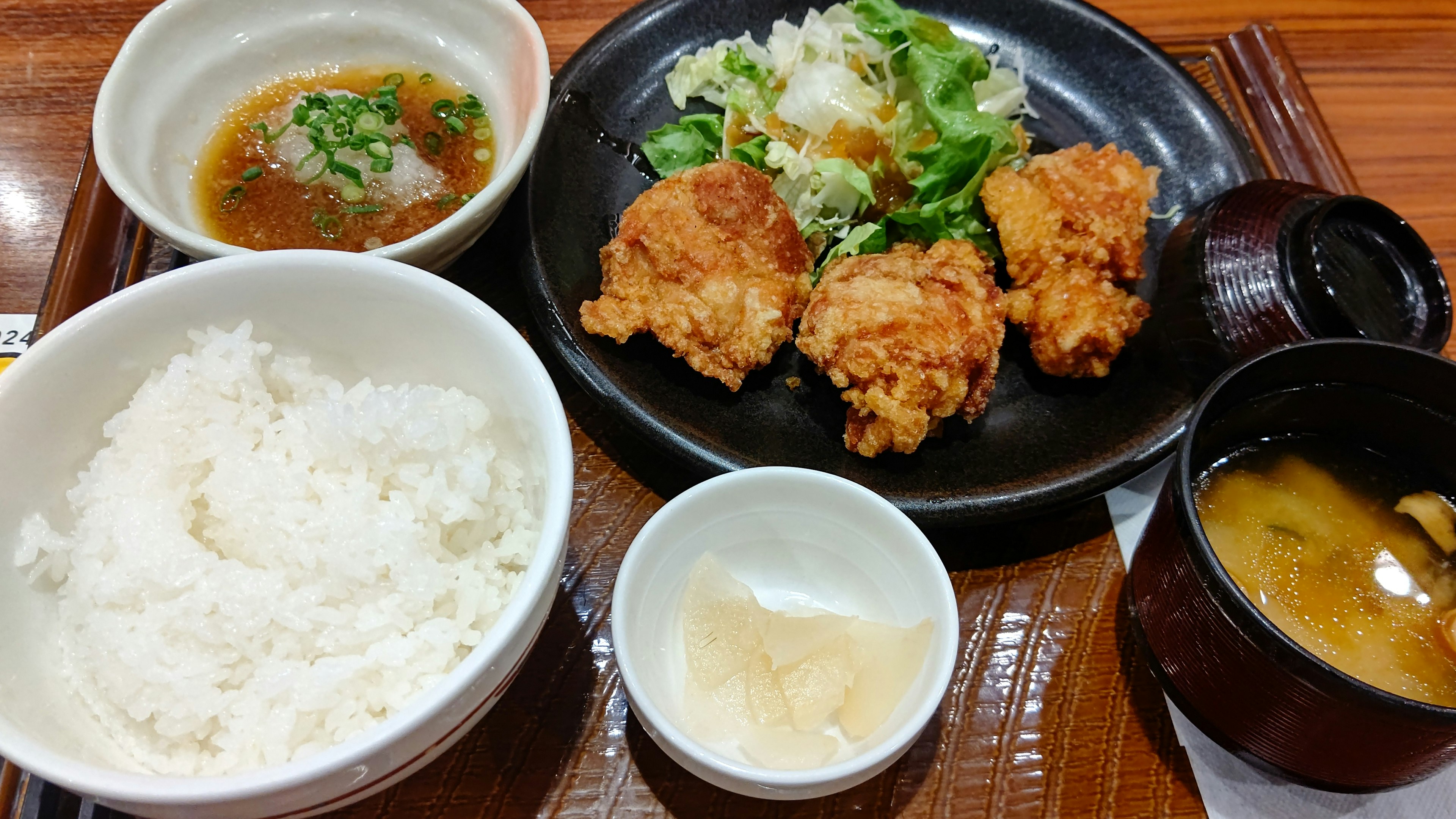 Japanese meal featuring fried chicken, salad, rice, and miso soup