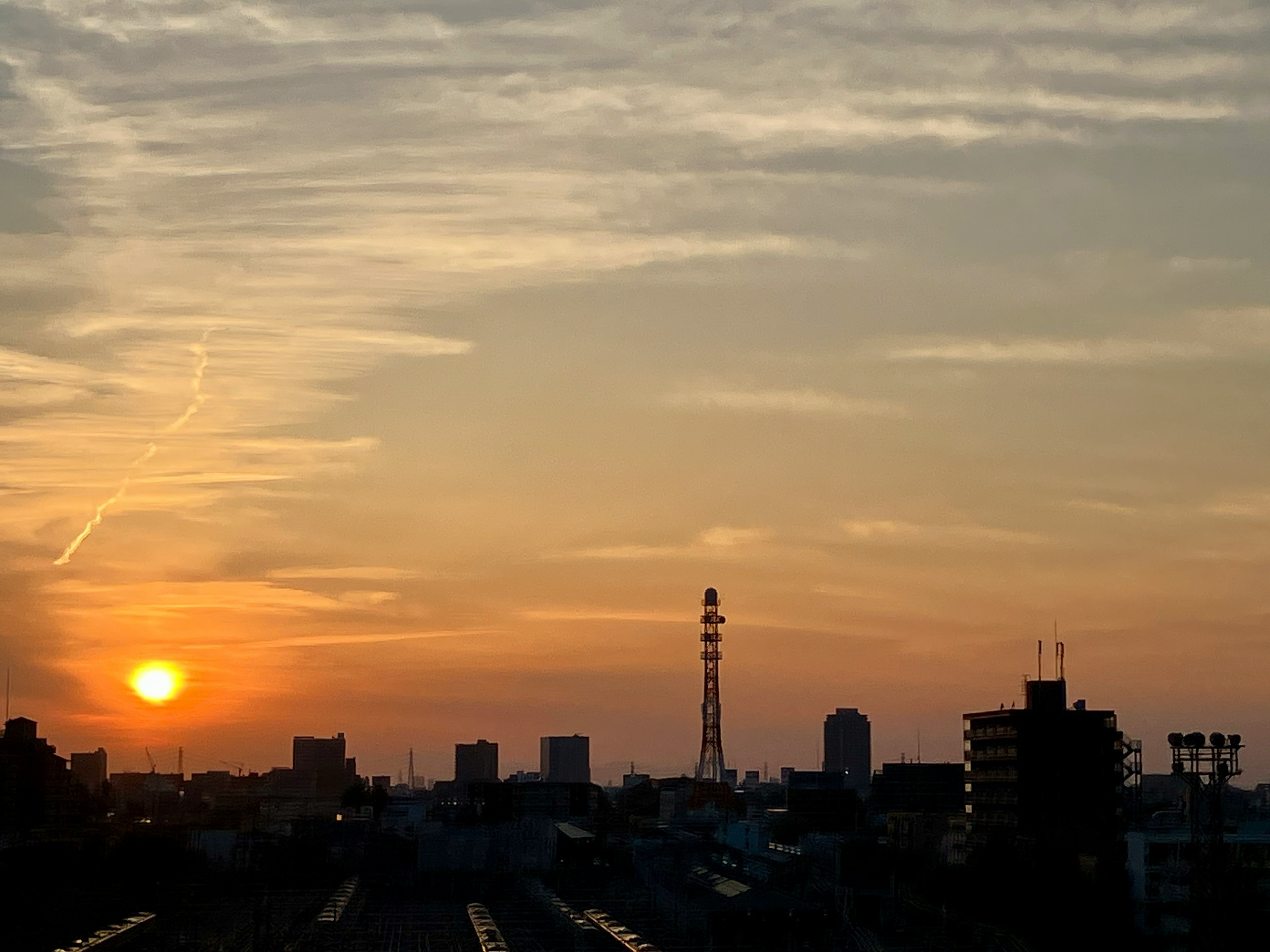 Skyline urbana al tramonto con una alta torre di radio