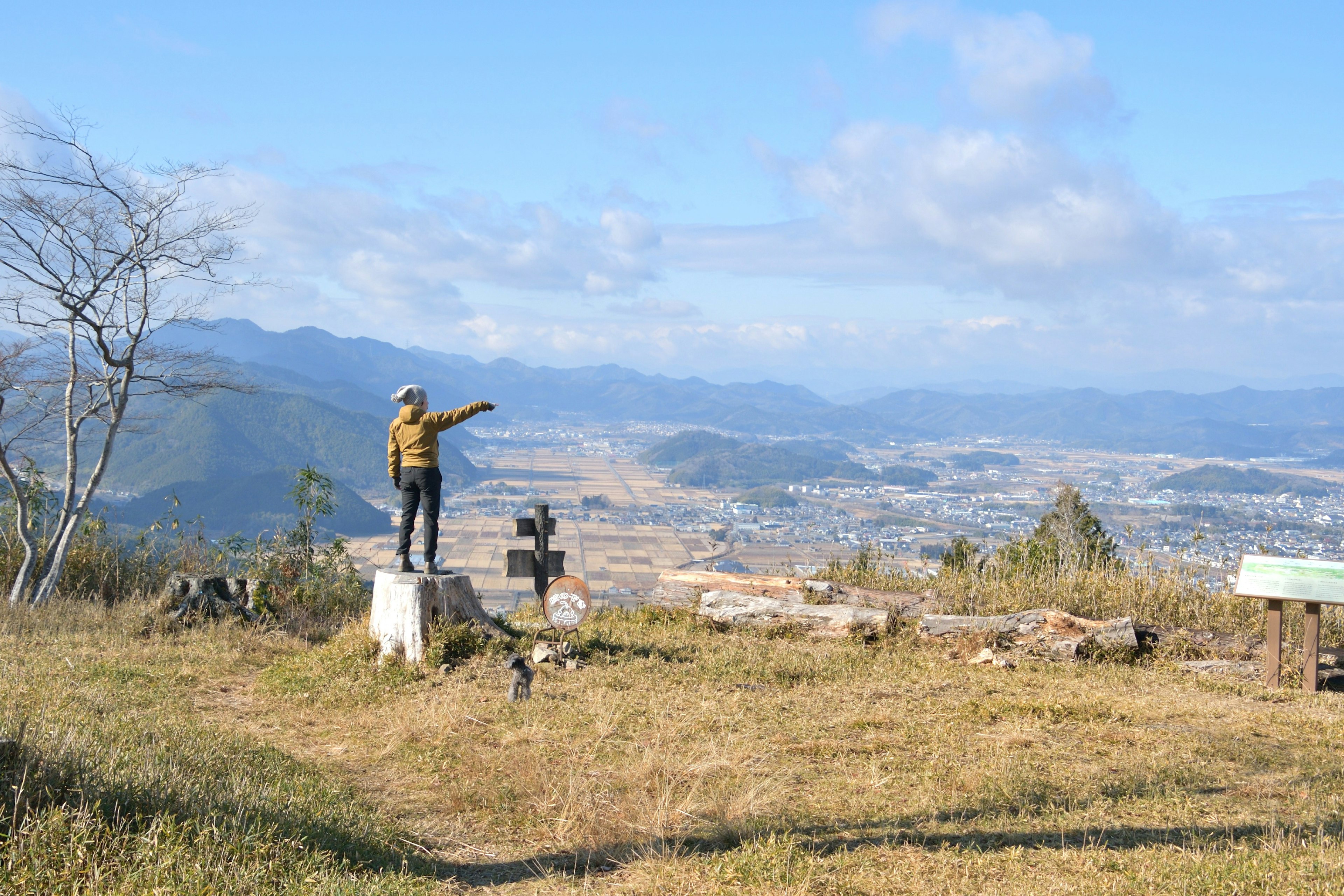 Orang berdiri di puncak gunung menunjuk ke kejauhan