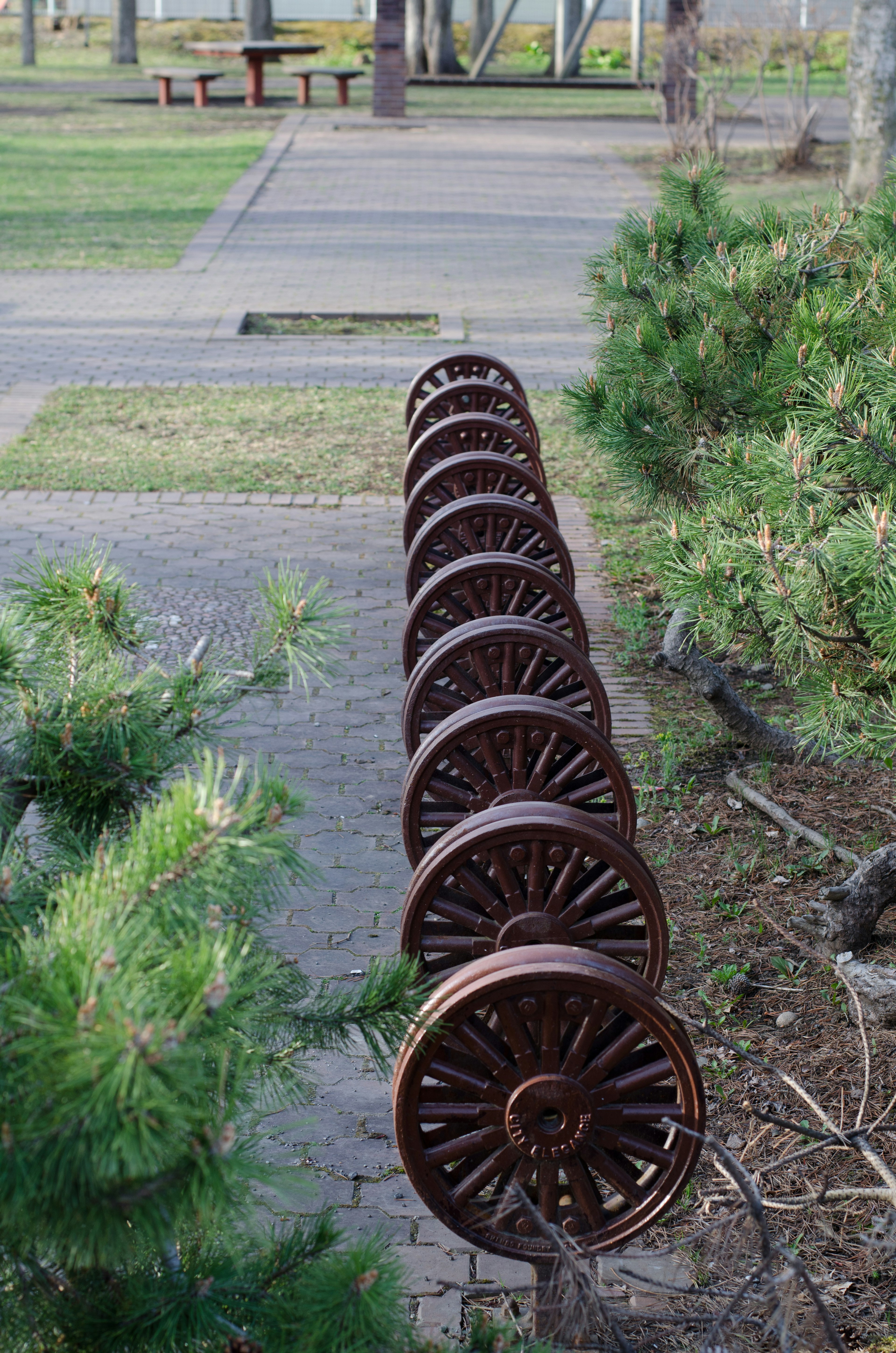 Row of circular objects resembling wheels in a park setting