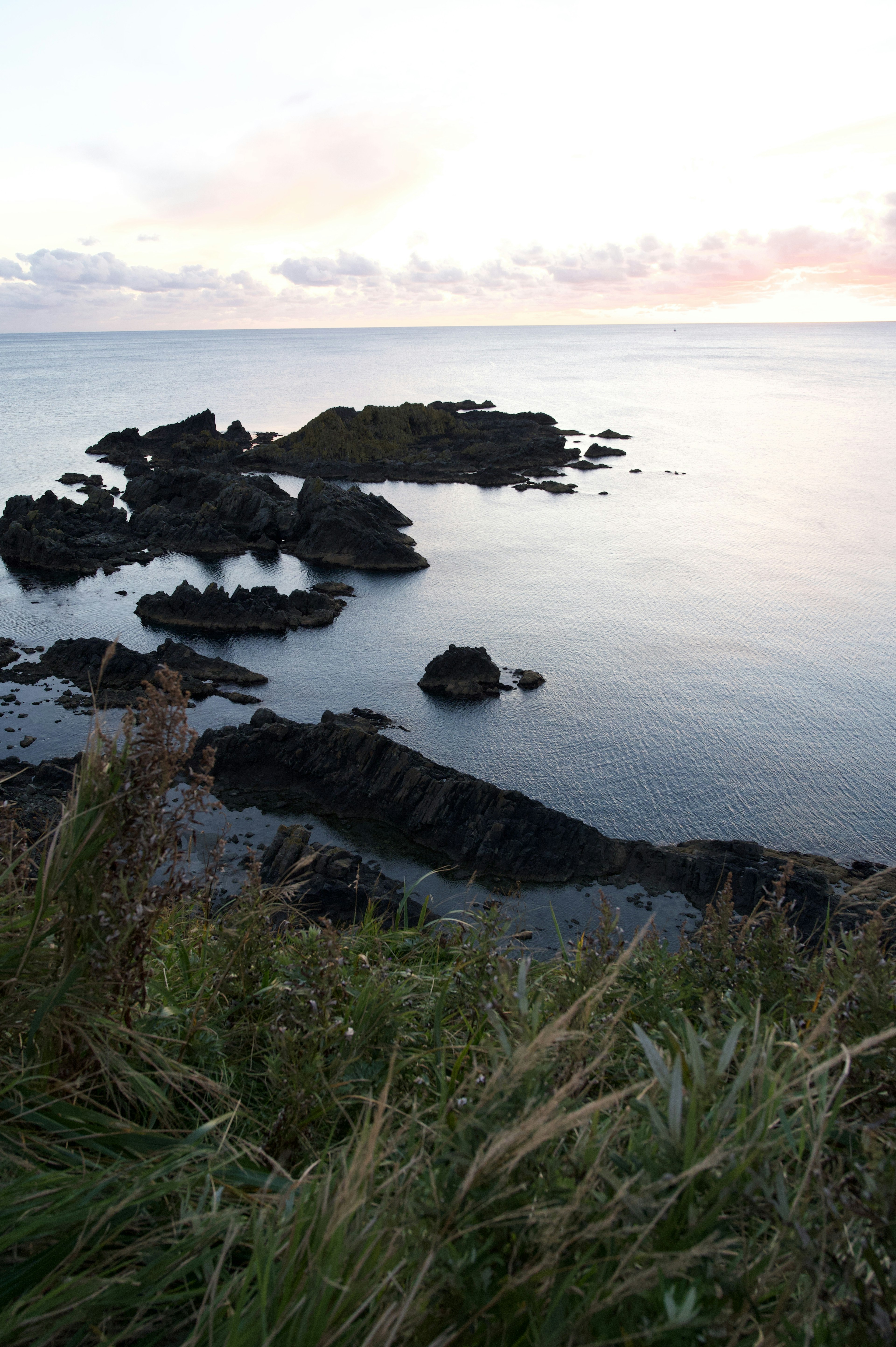 Paisaje marino tranquilo con costa rocosa y suave luz del atardecer