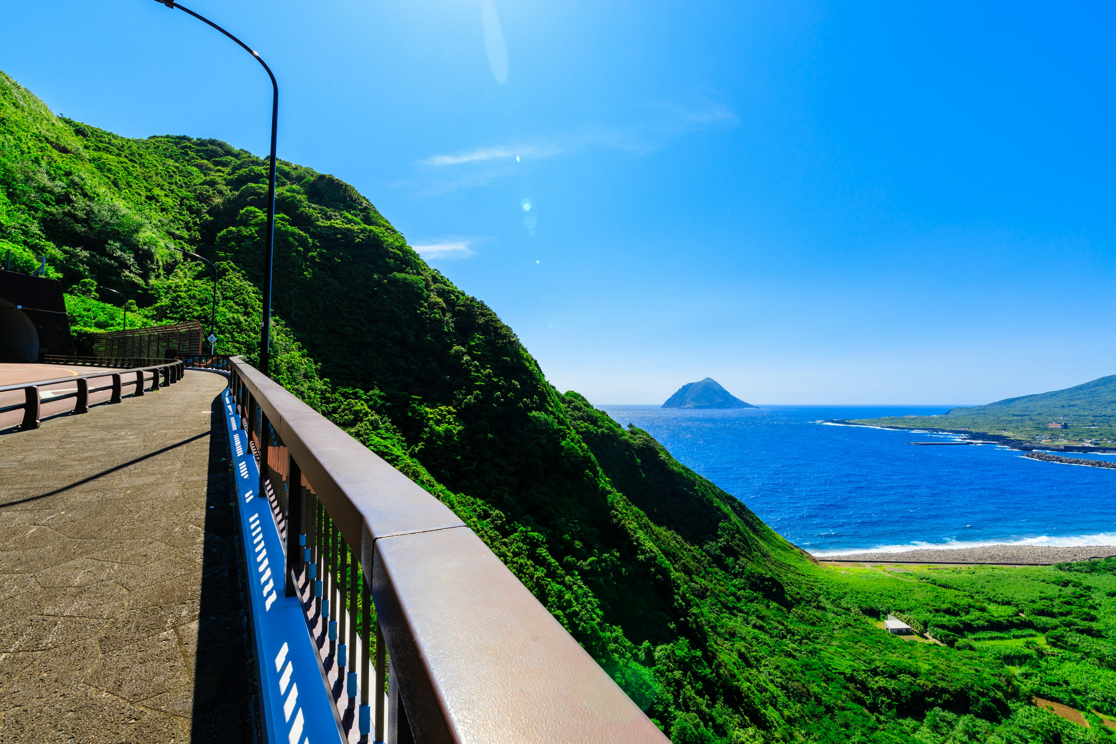 Vue pittoresque d'une route côtière avec des collines verdoyantes et un océan bleu