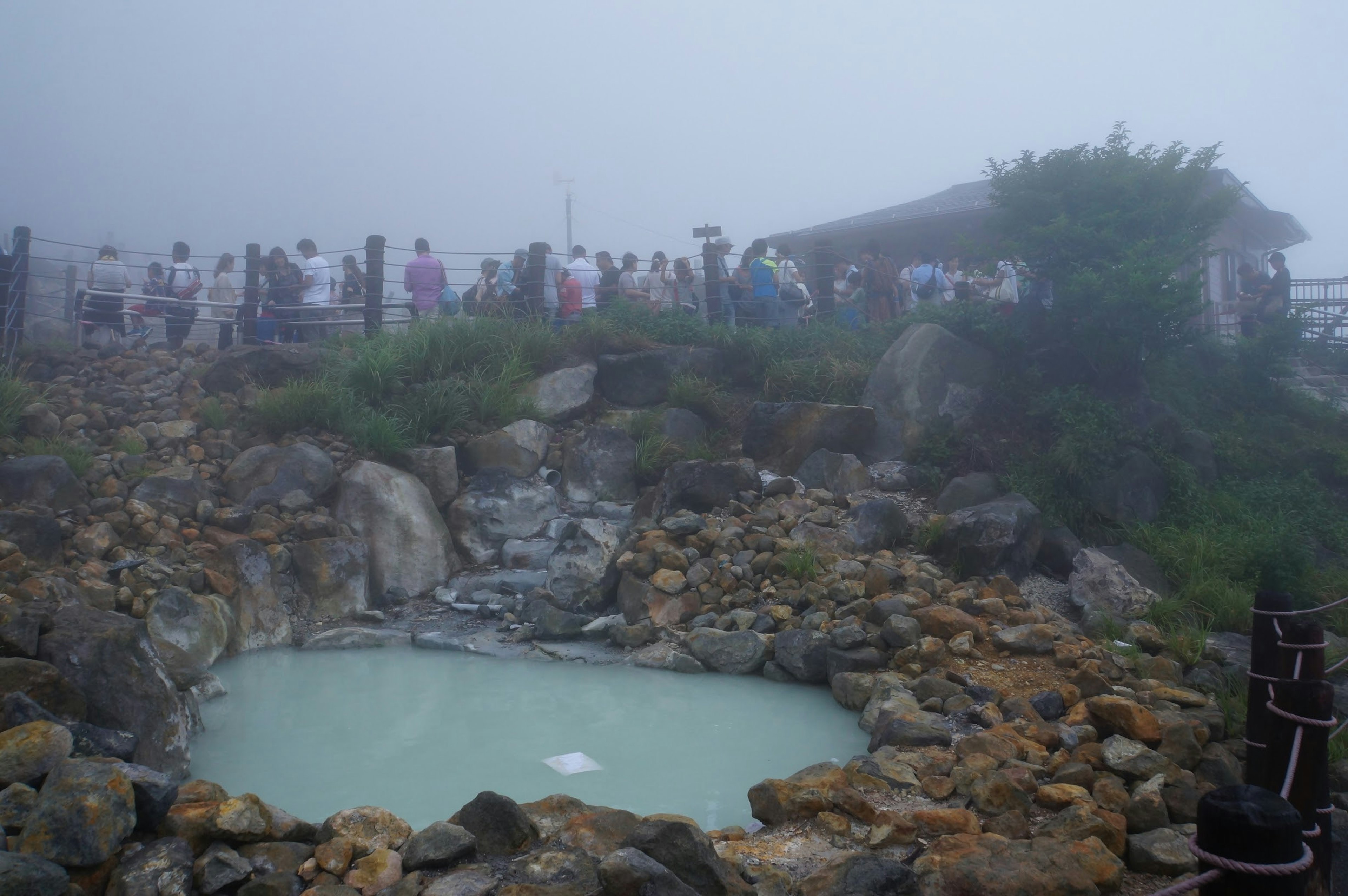 Manantial caliente rodeado de niebla con una multitud de turistas