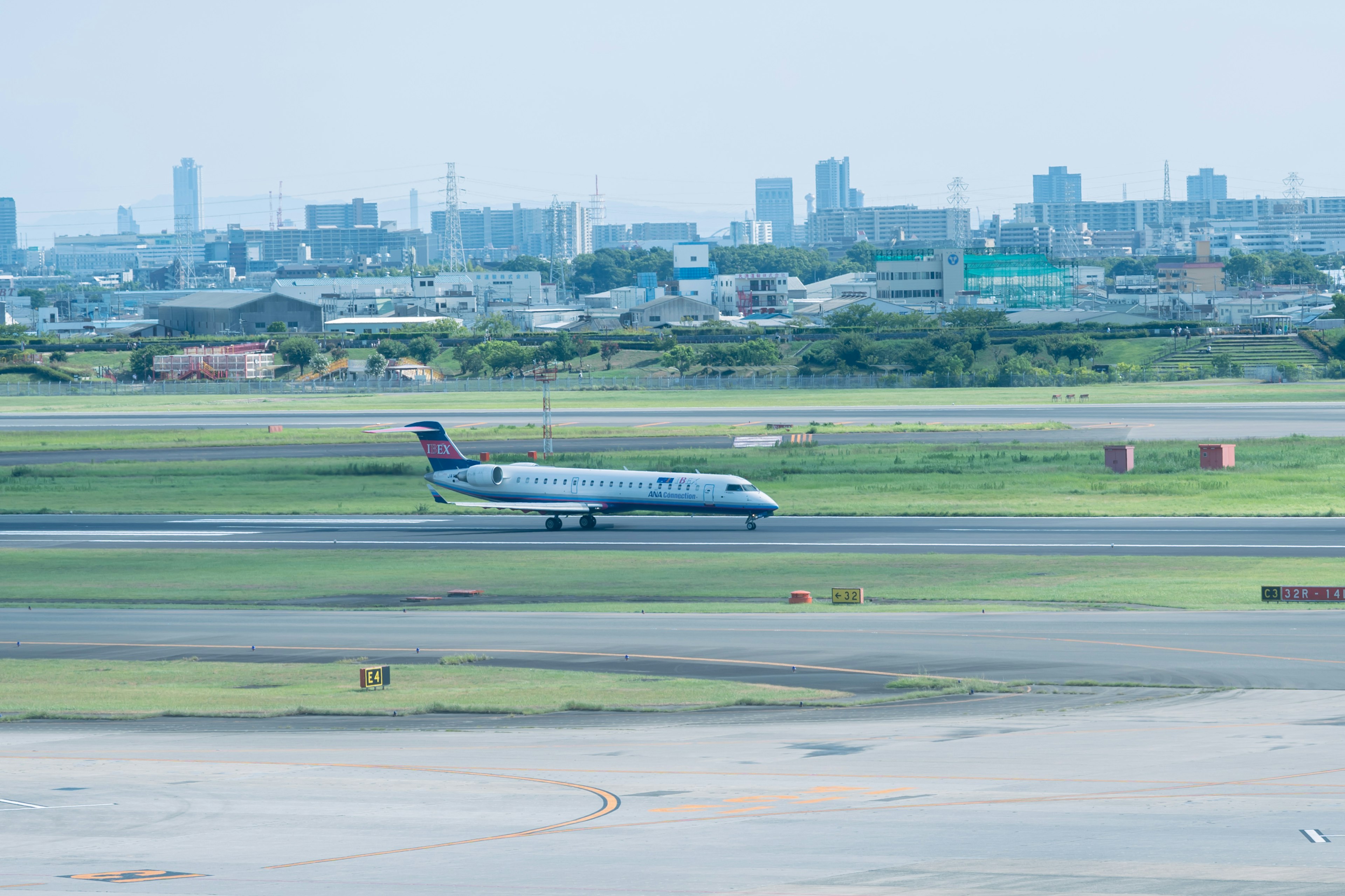 Airplane taking off at an airport with a city skyline in the background