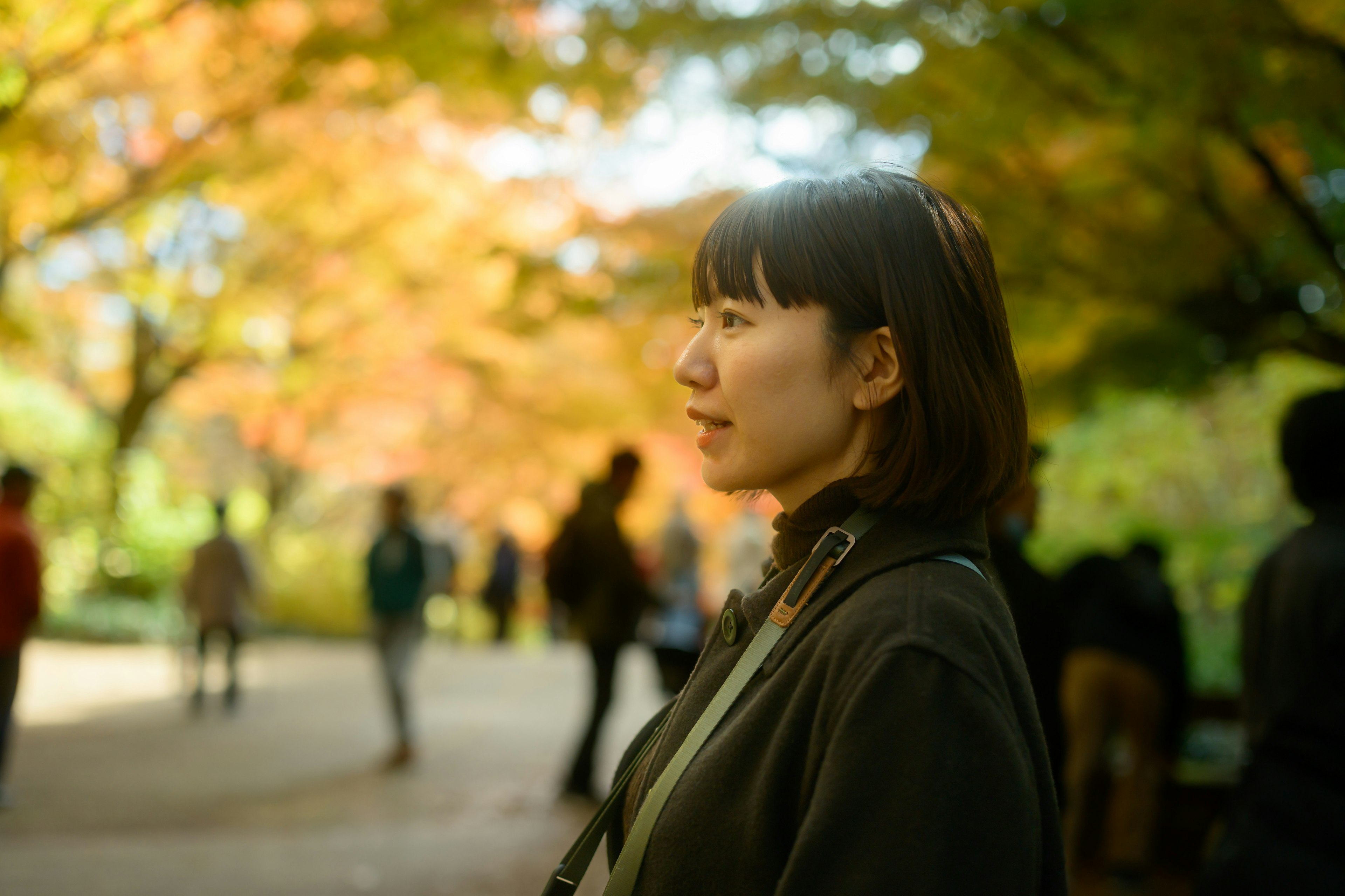 Profil d'une femme dans un parc avec des feuilles d'automne en arrière-plan