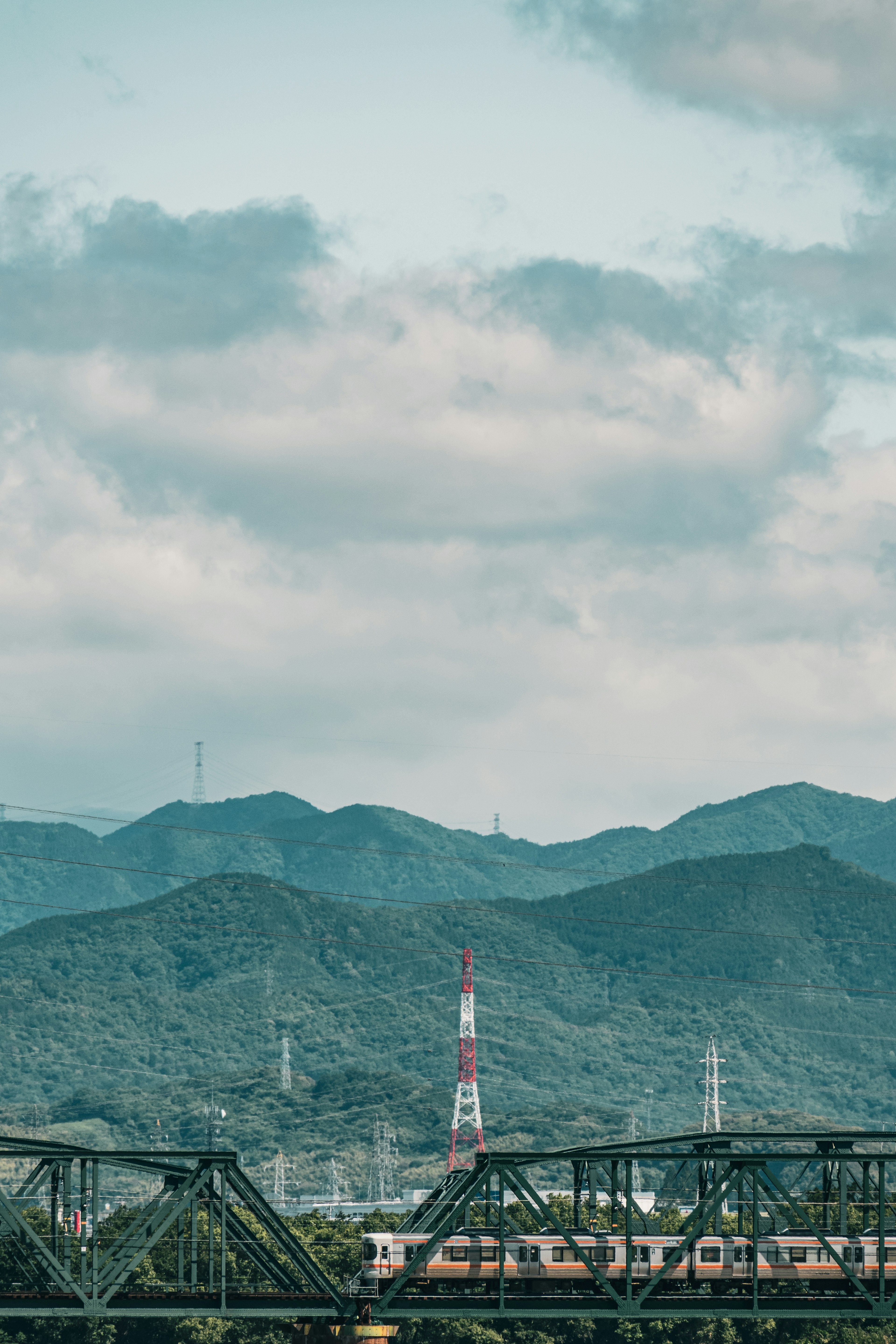 山々の背景に赤と白の送信塔が見える風景