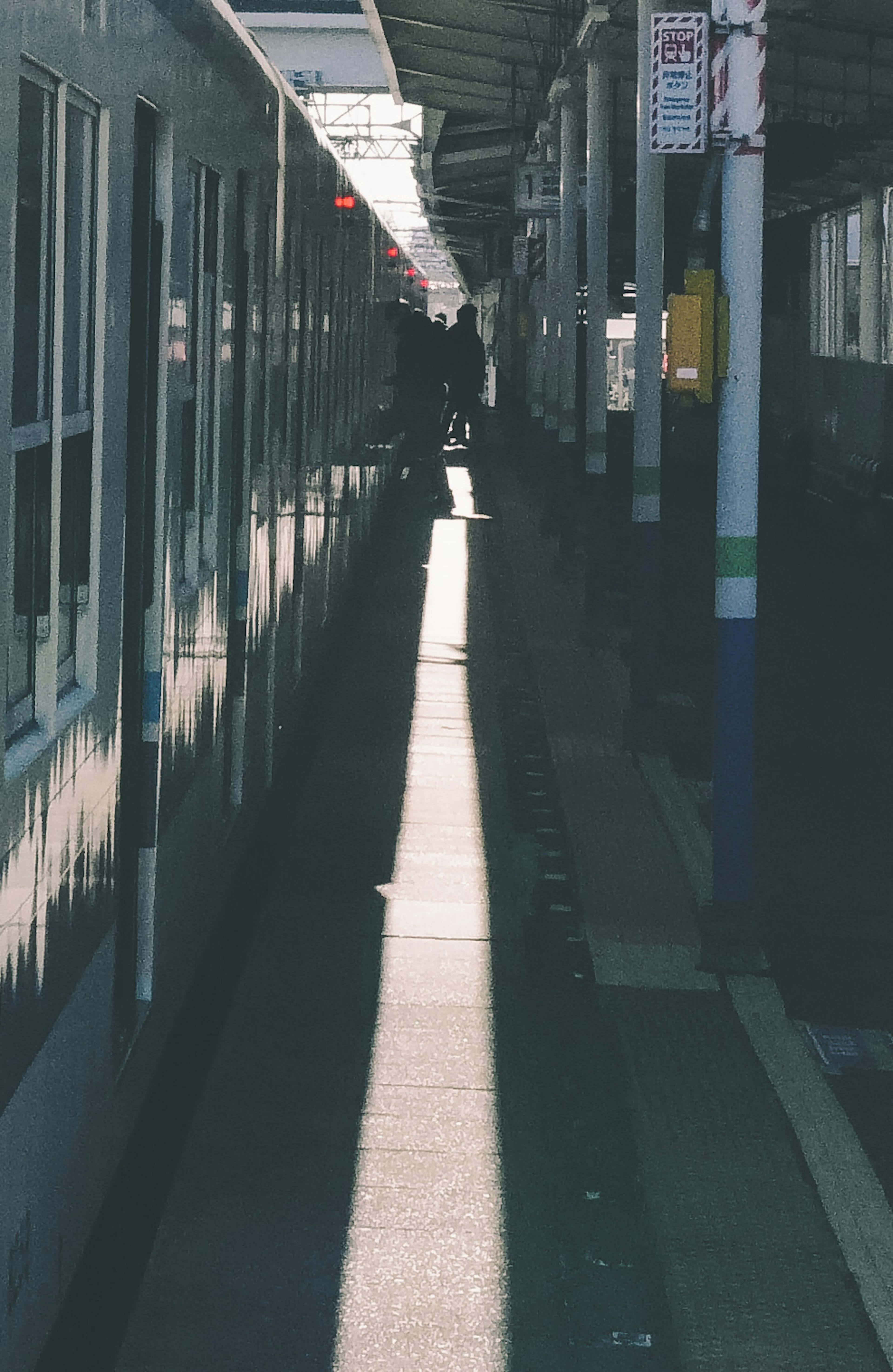 Zug auf einem Bahnsteig mit Schatten und Personen