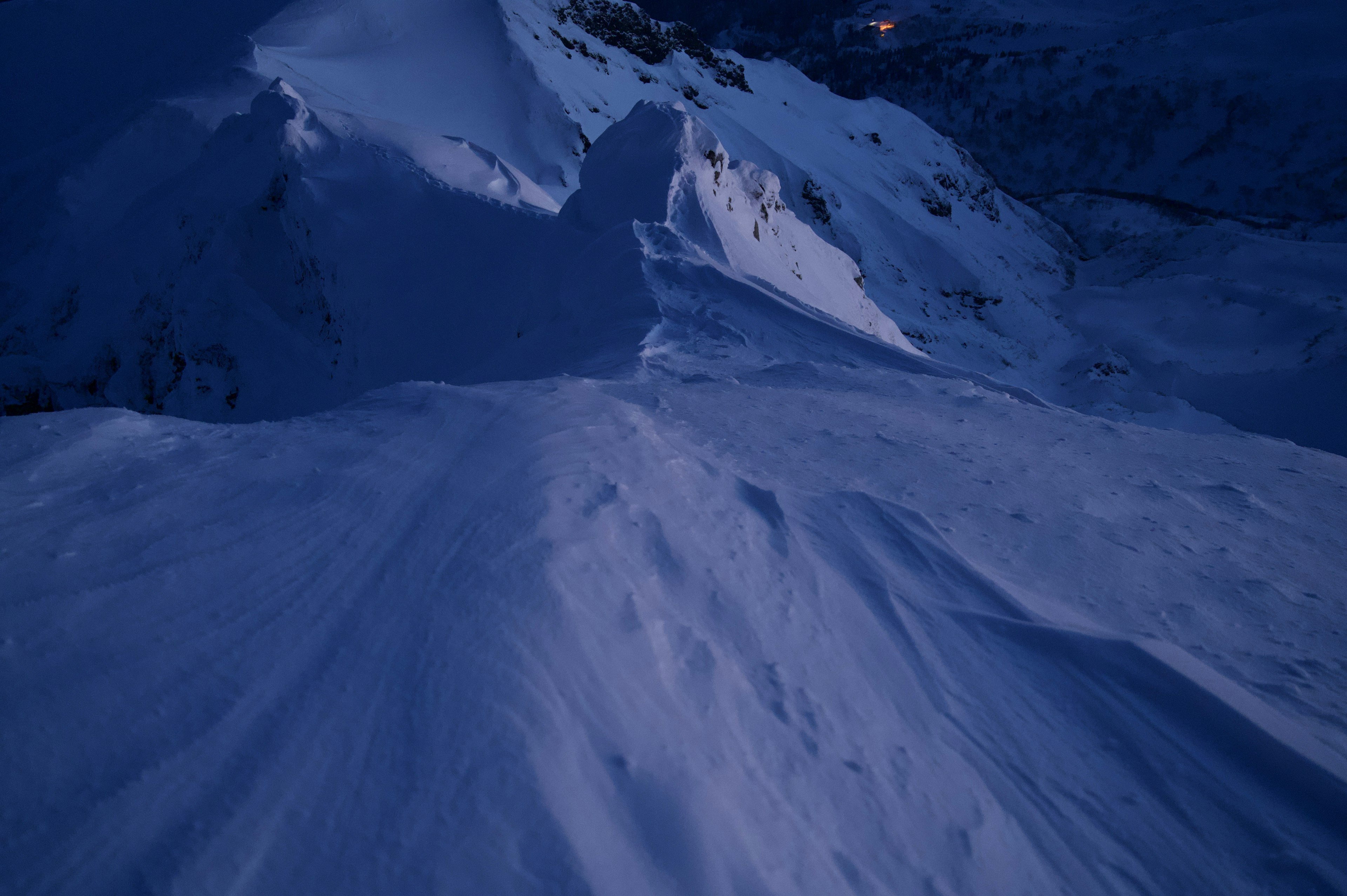 Pendio di montagna coperto di neve illuminato da una luce blu scura