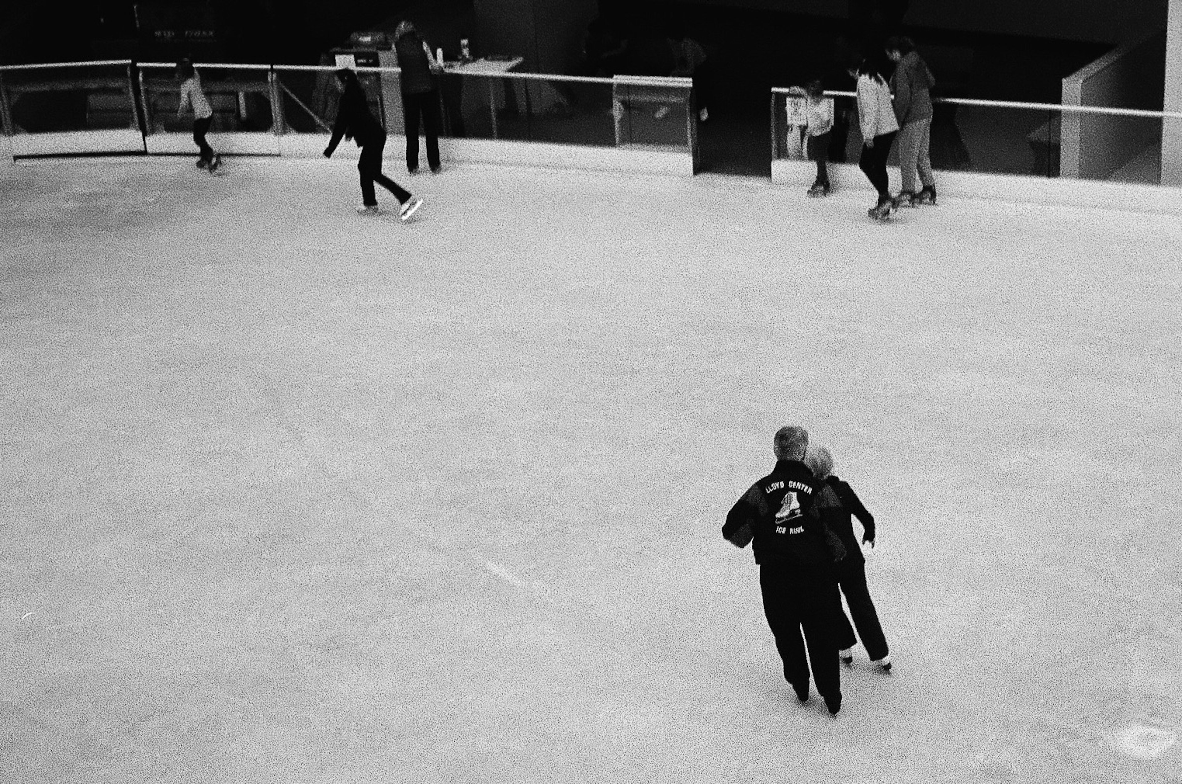 Black and white photo of people skating on an ice rink