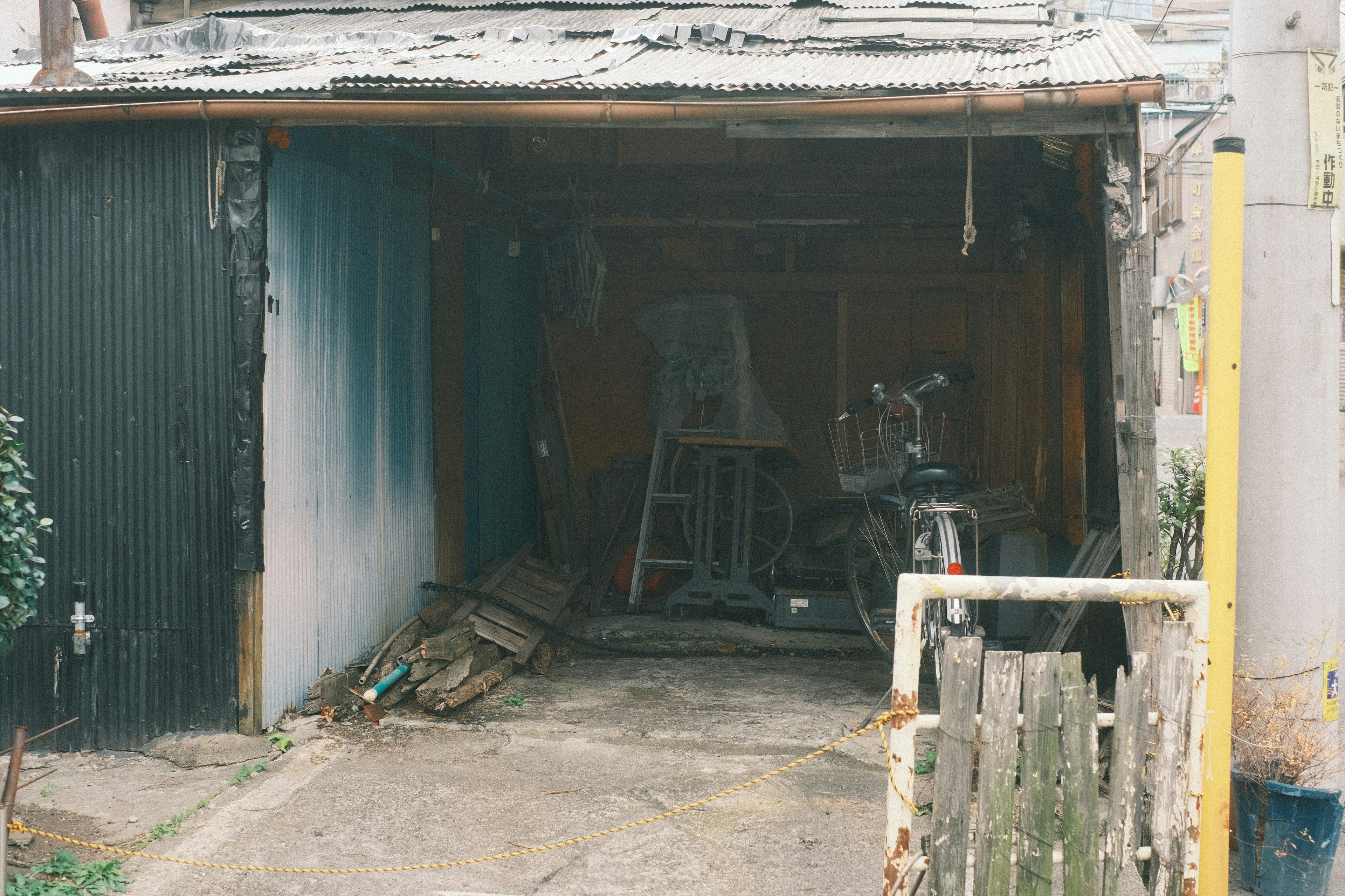 Exterior of an old garage featuring wooden tools and a motorcycle