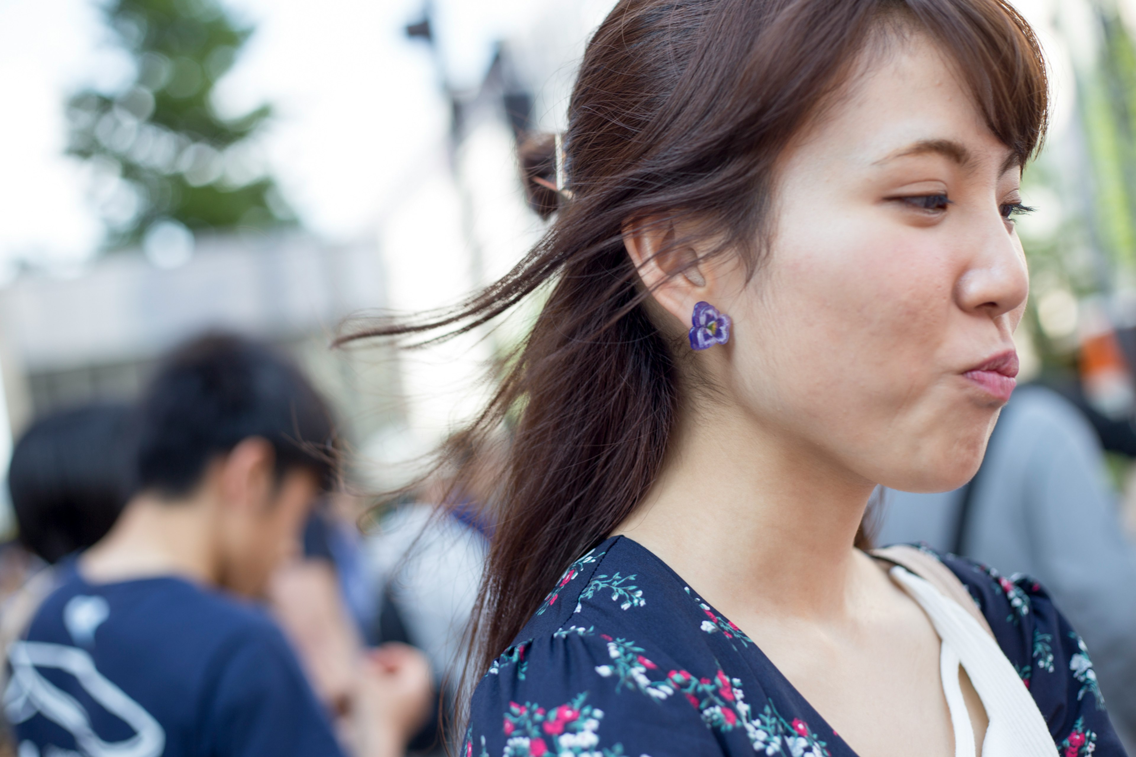 女性が風になびく髪を持ち紫のイヤリングを着けている