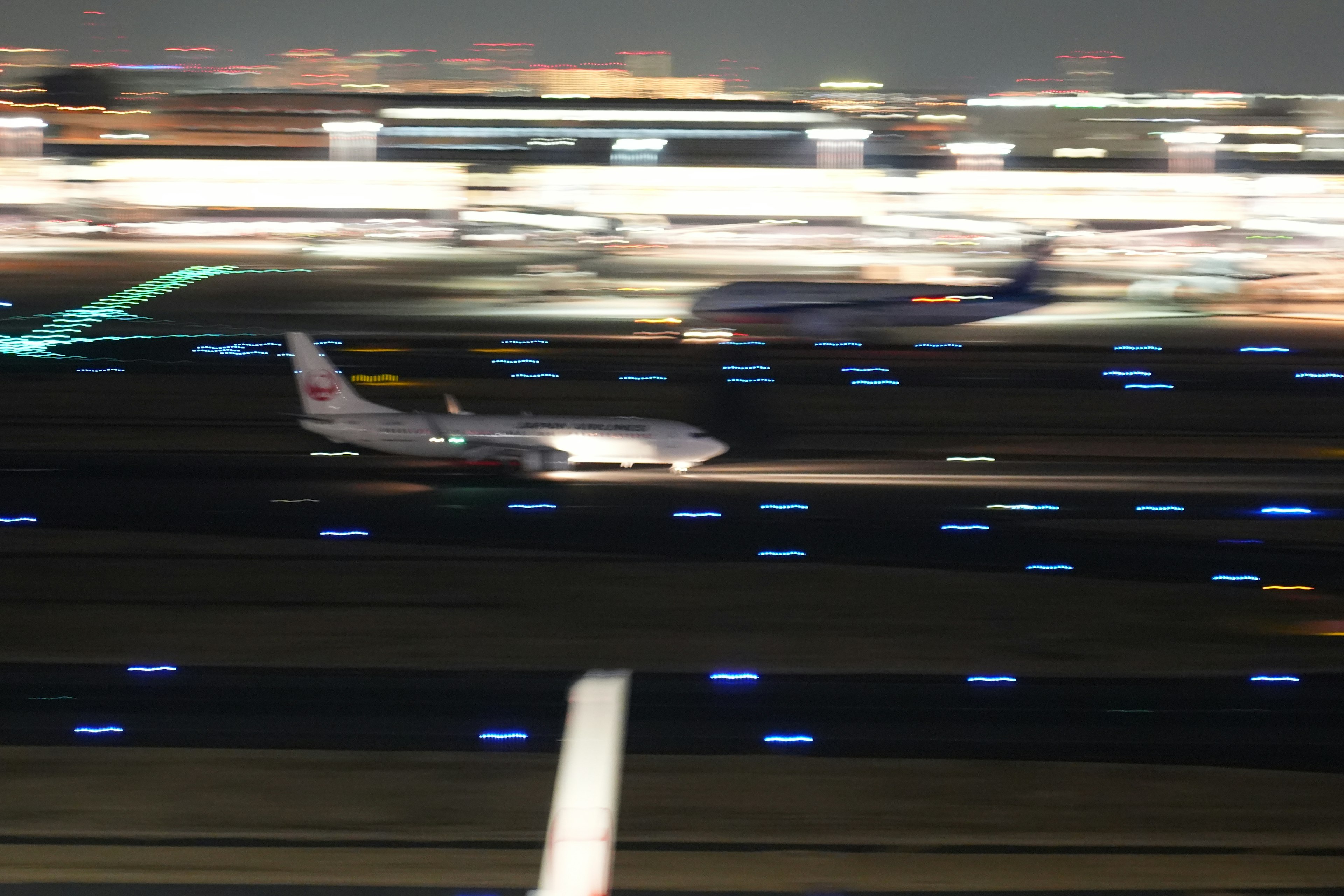 Un avión rodando por una pista de noche con luces iluminadas