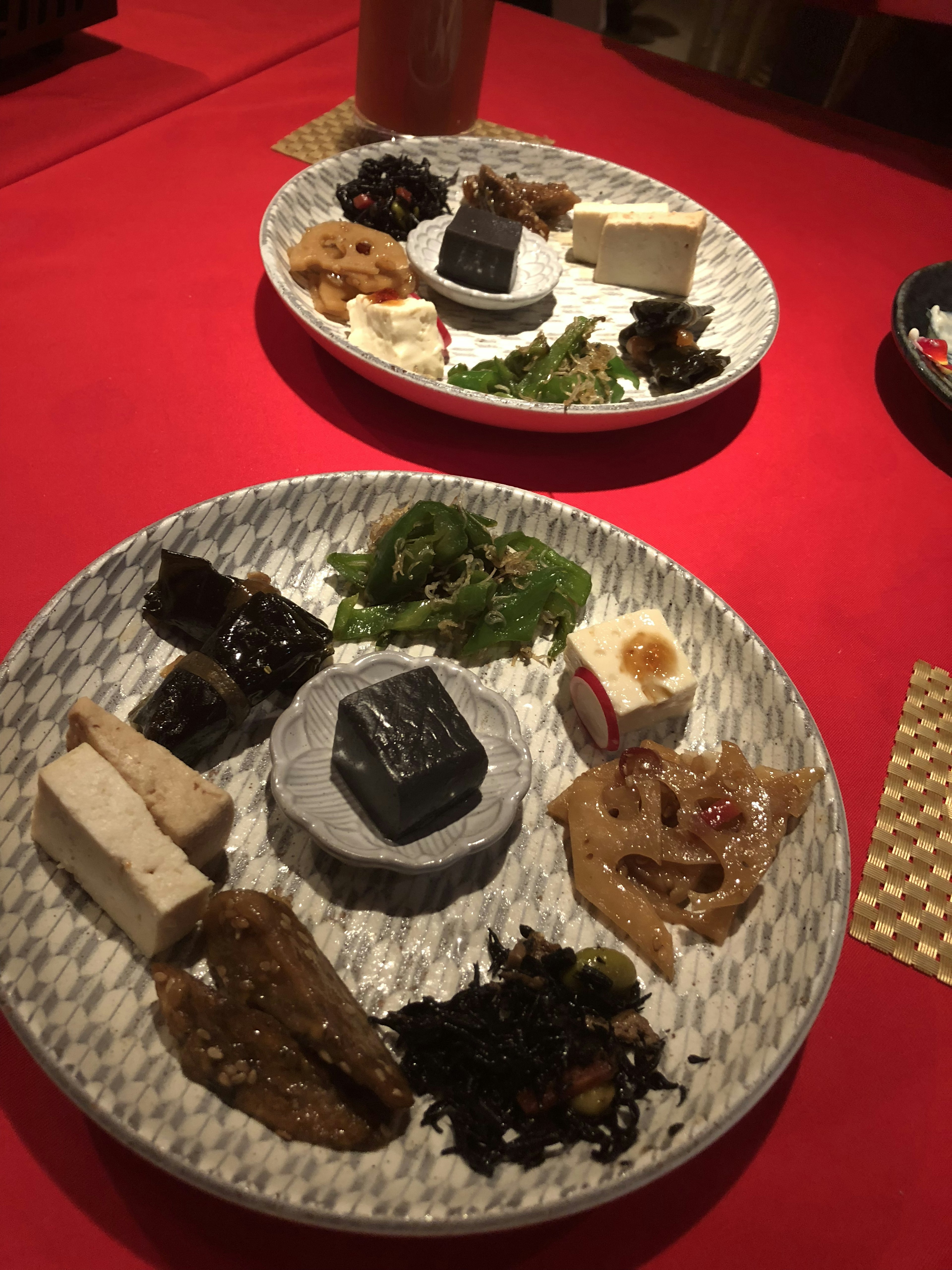 Deux assiettes d'apéritifs japonais variés sur une table rouge