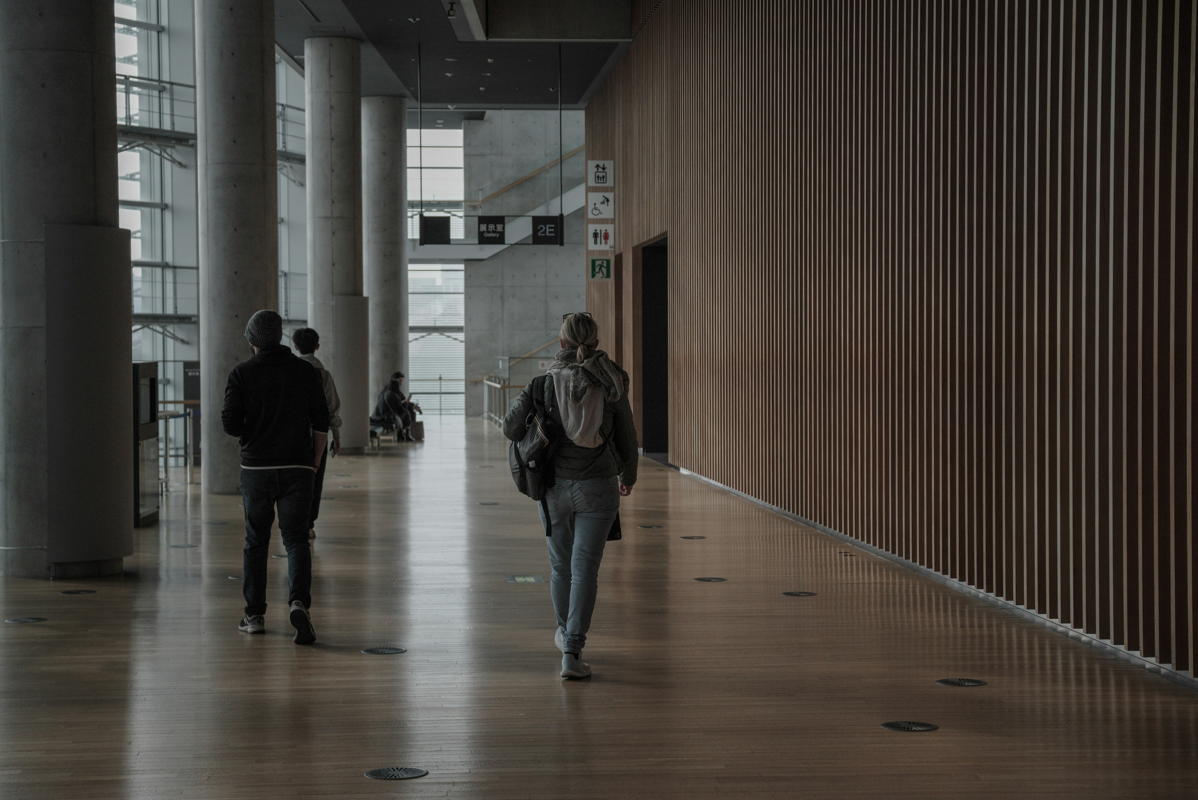 Due persone che camminano in un corridoio moderno con pareti in legno