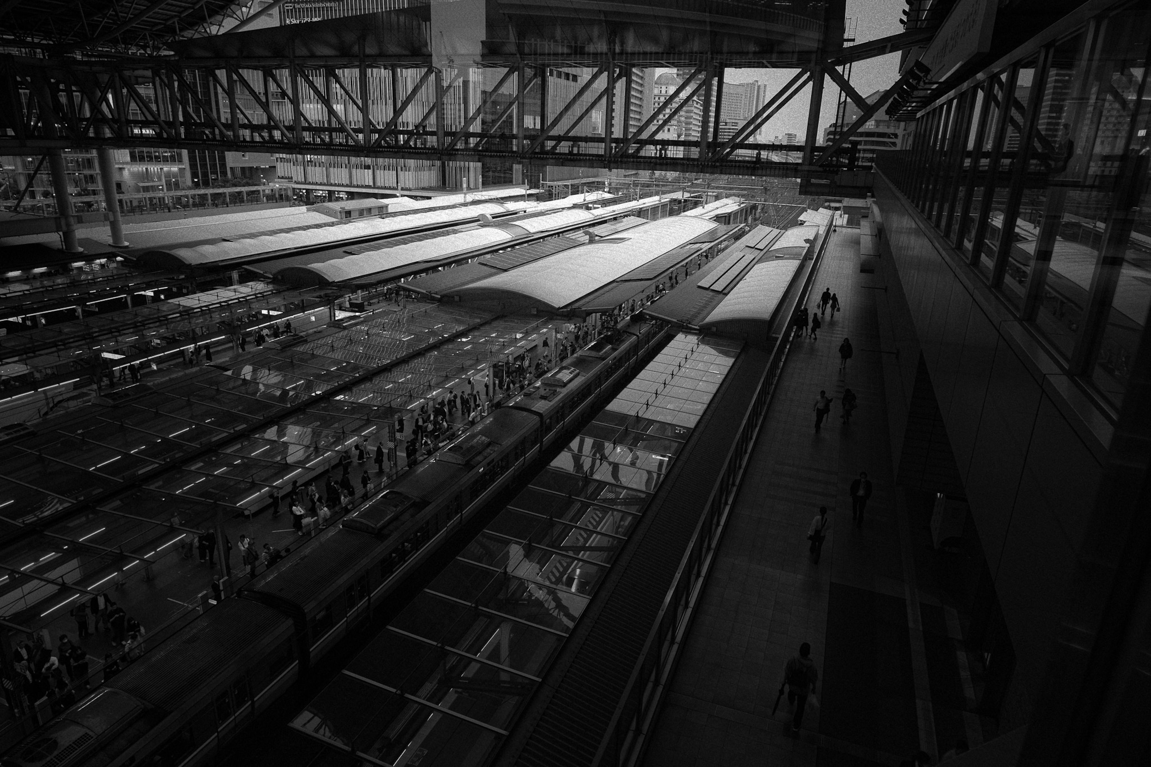 Black and white image of a modern train station with people walking