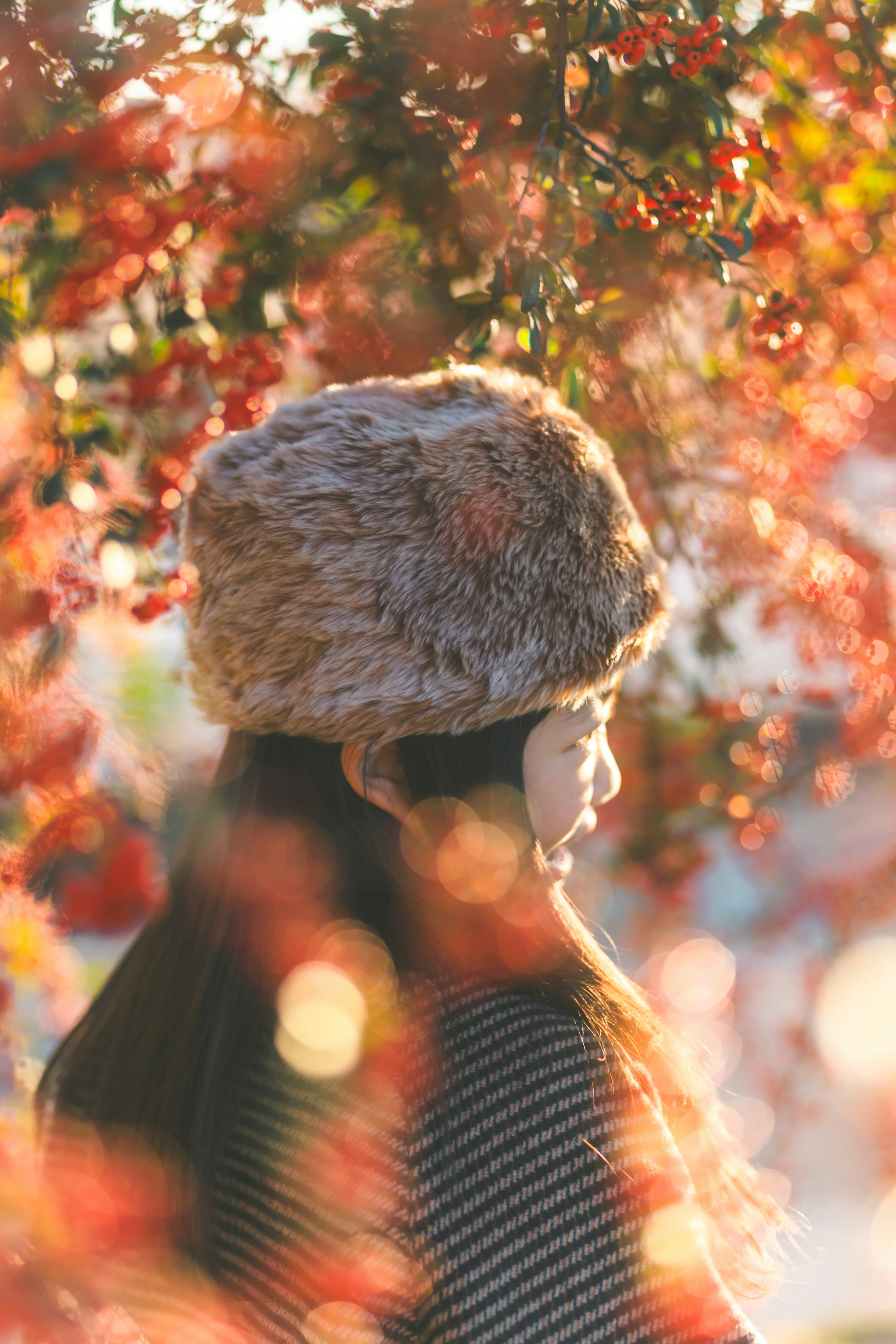 秋の葉の中で毛皮の帽子をかぶった女性の横顔