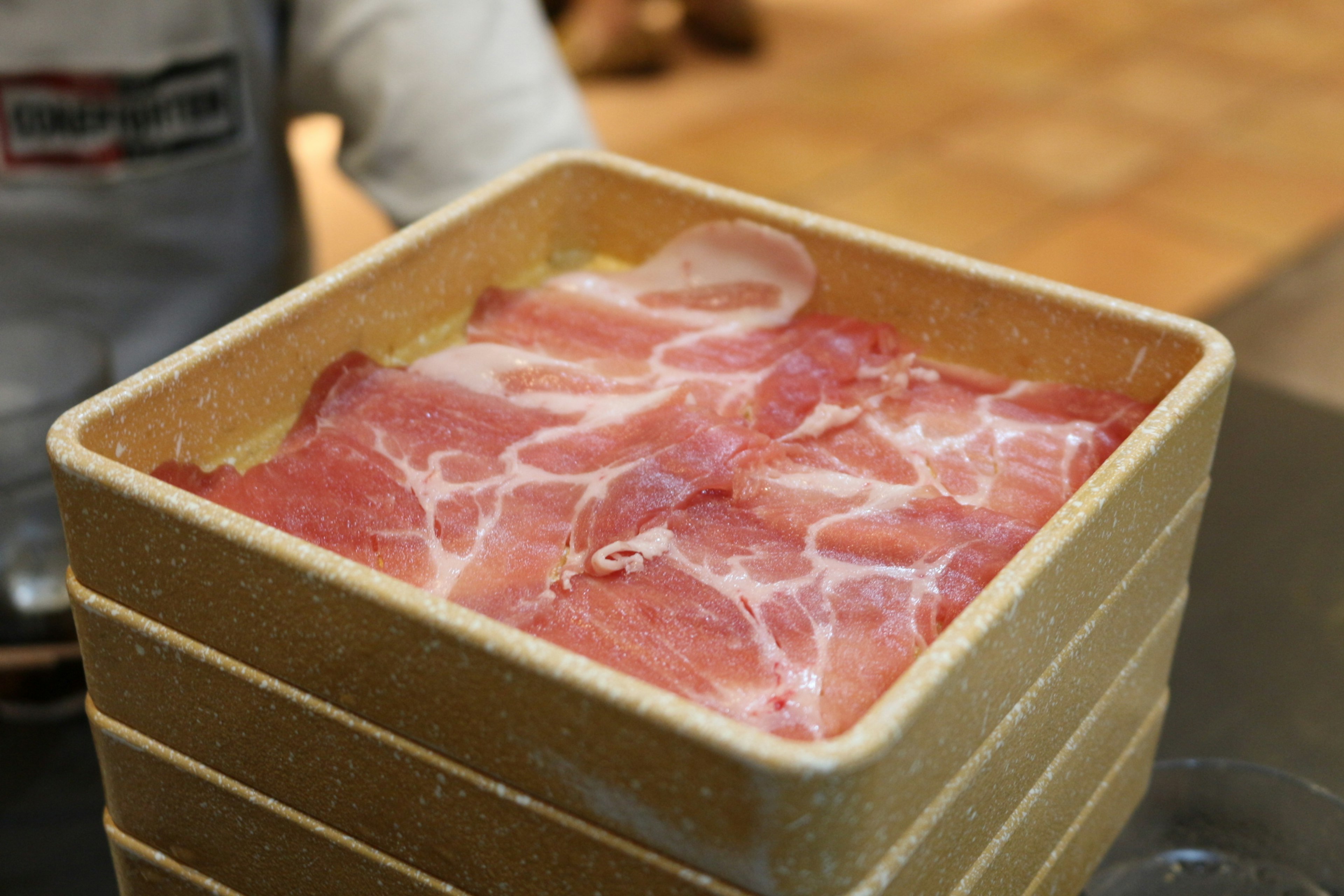 Square container filled with thinly sliced meat