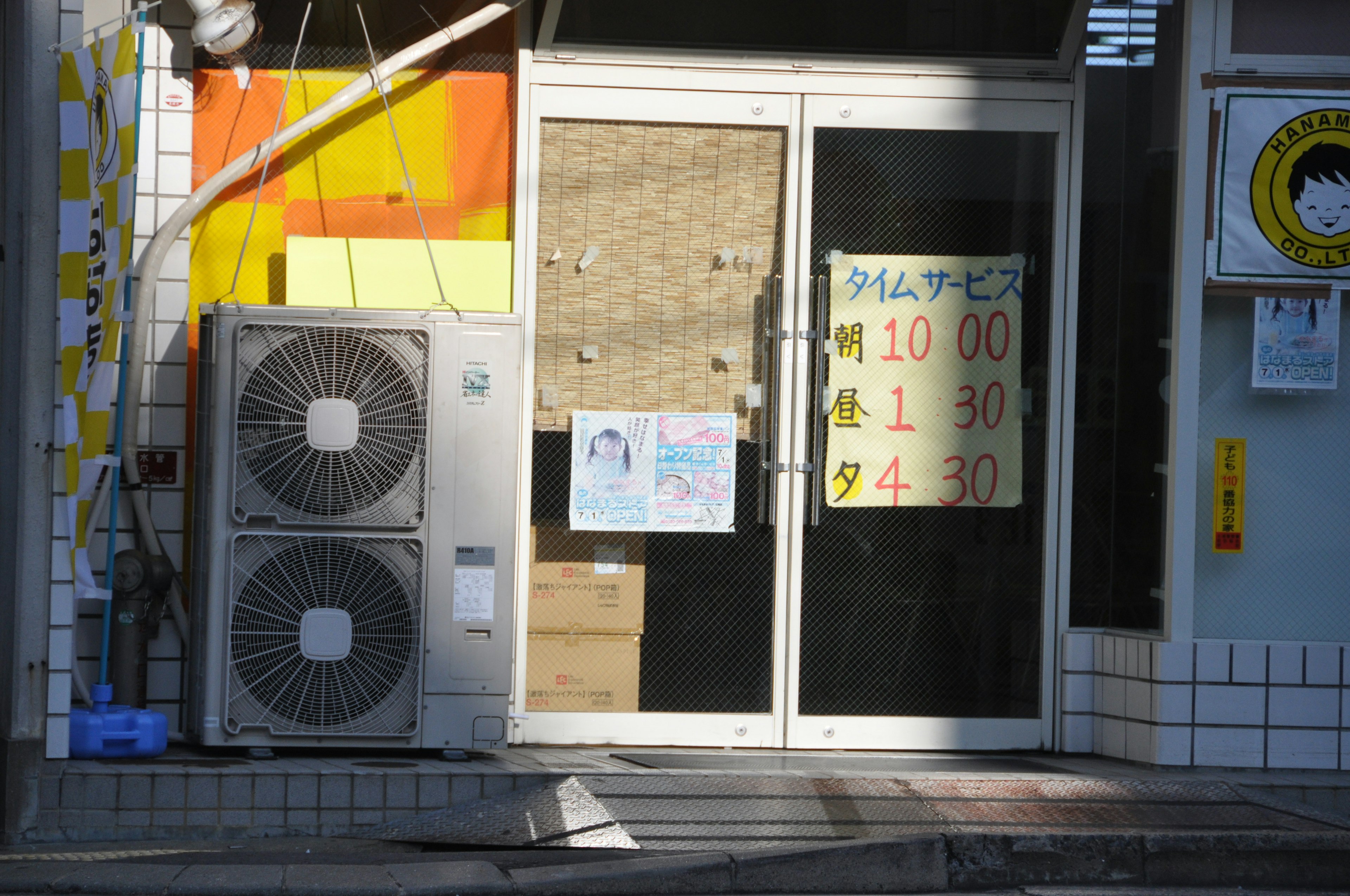 Entrance of a shop featuring air conditioning units and posted business hours