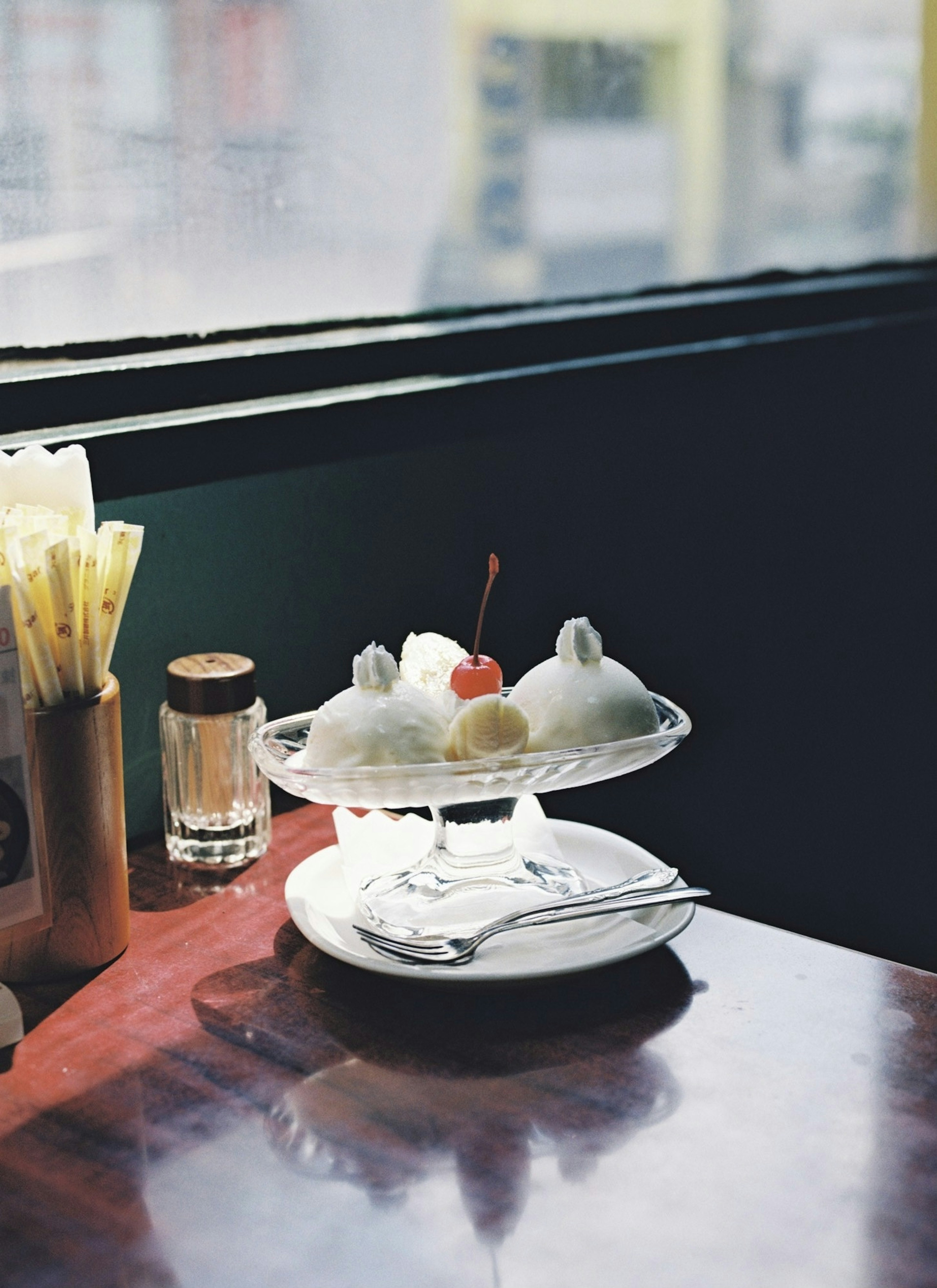 A dessert plate with ice cream topped with a cherry on a table