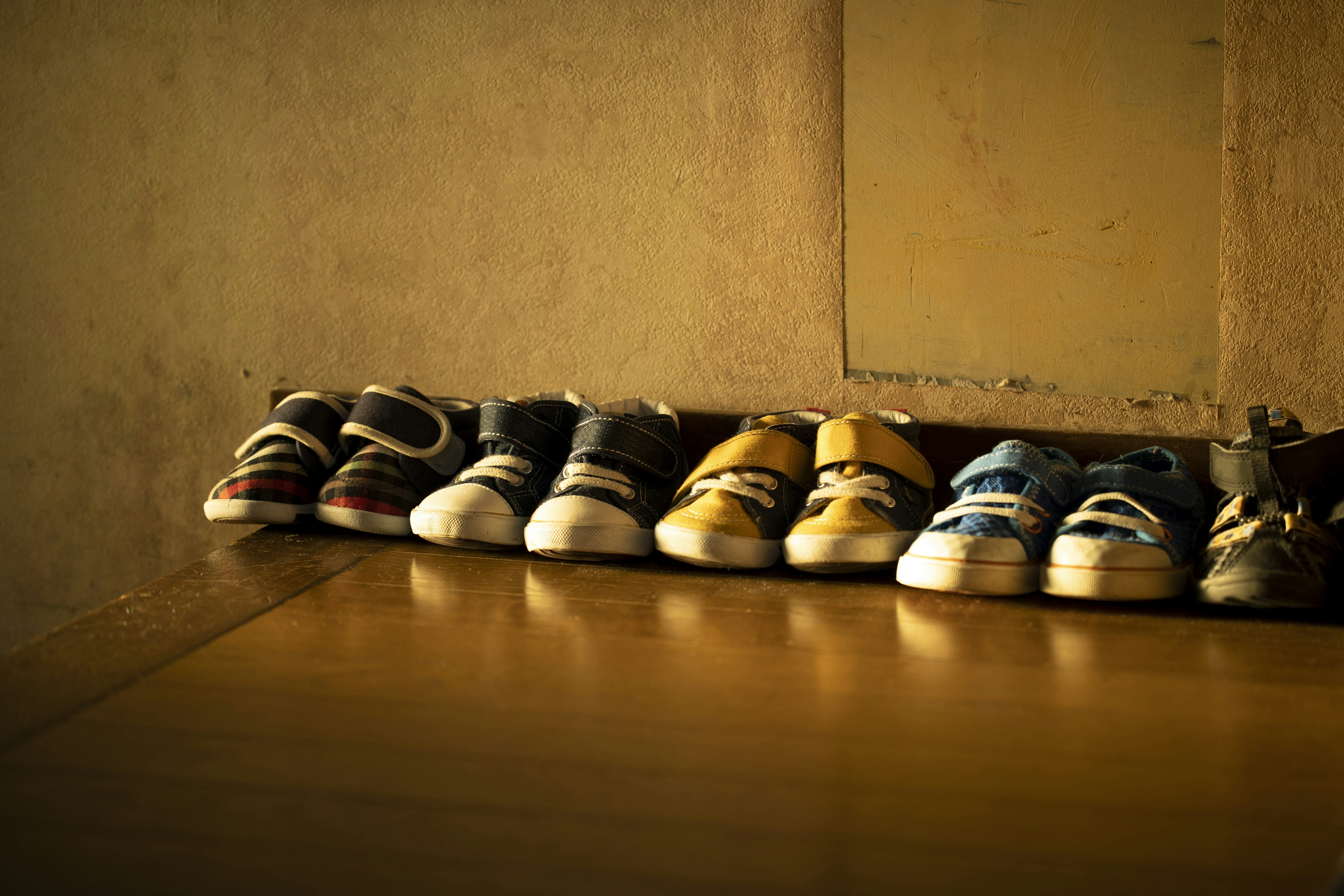 Una fila di scarpe da ginnastica varie disposte ordinatamente su un pavimento di legno