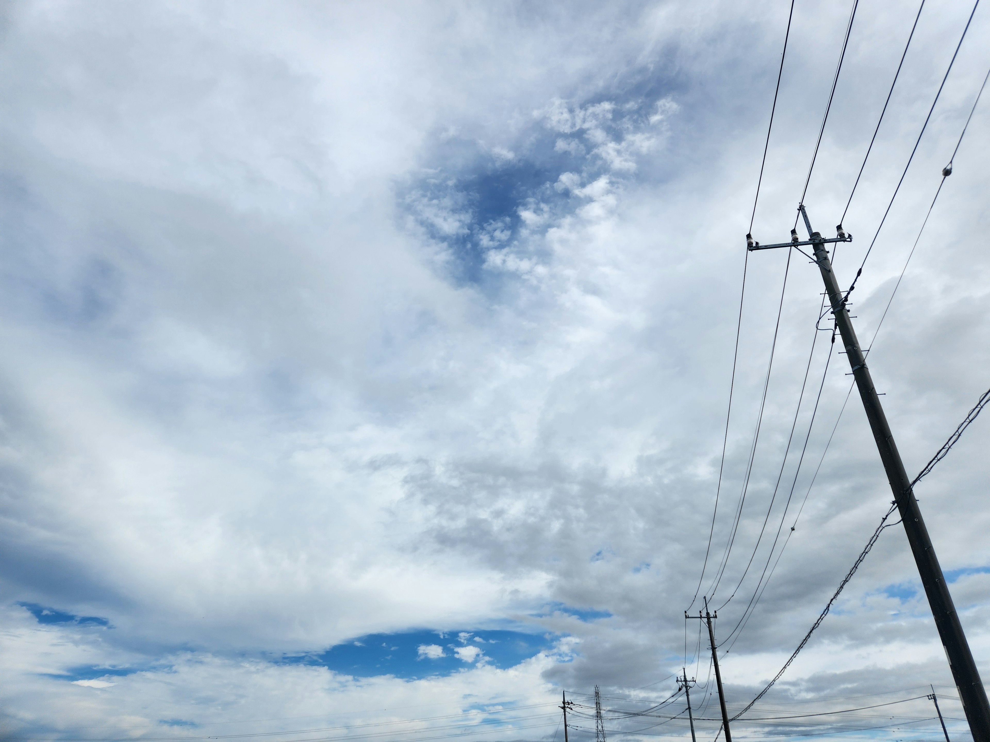 空に広がる雲と青空のコントラスト 電柱が並ぶ風景