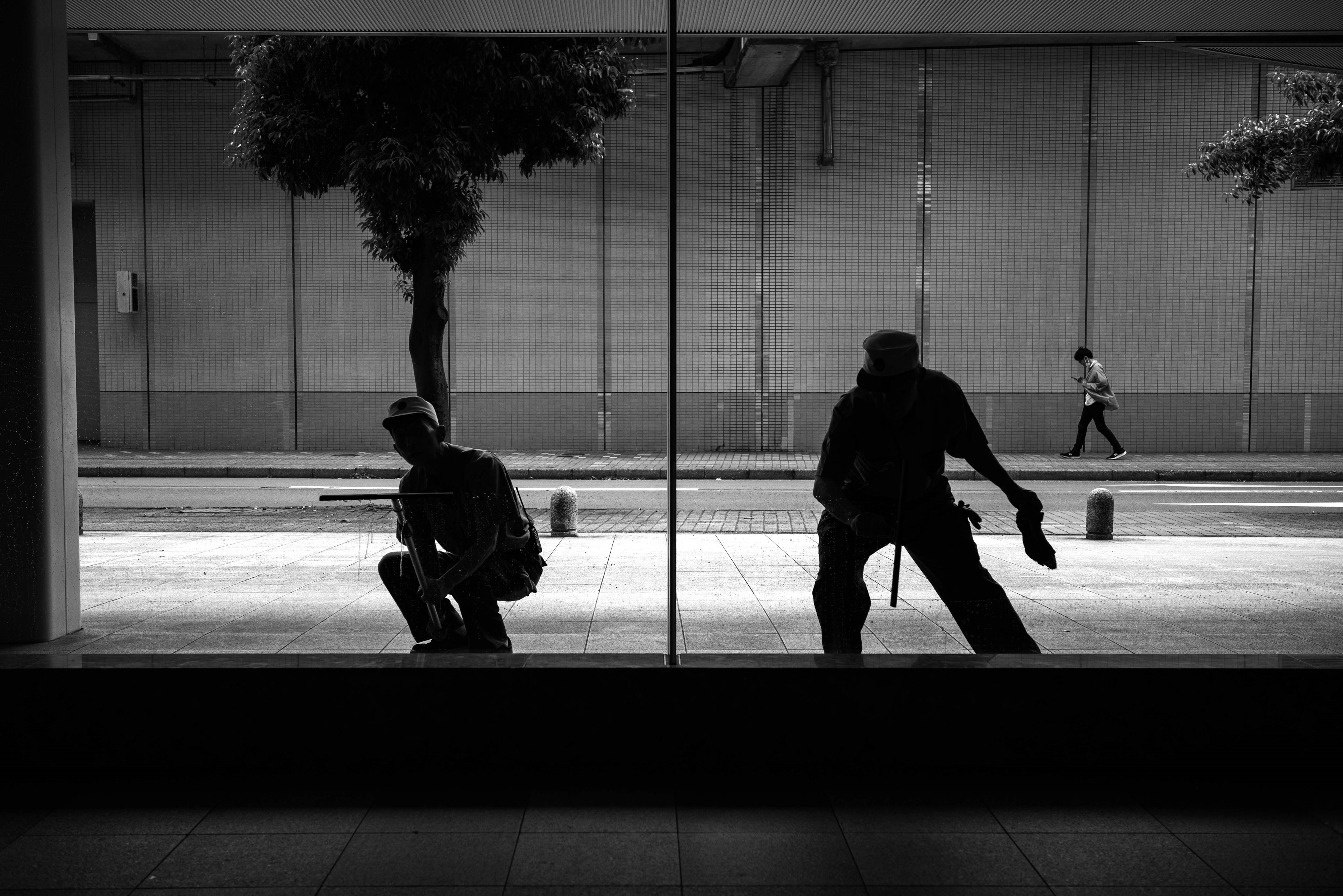 黒と白のコントラストで表現された二人の人物の影が窓に映っている都市の風景