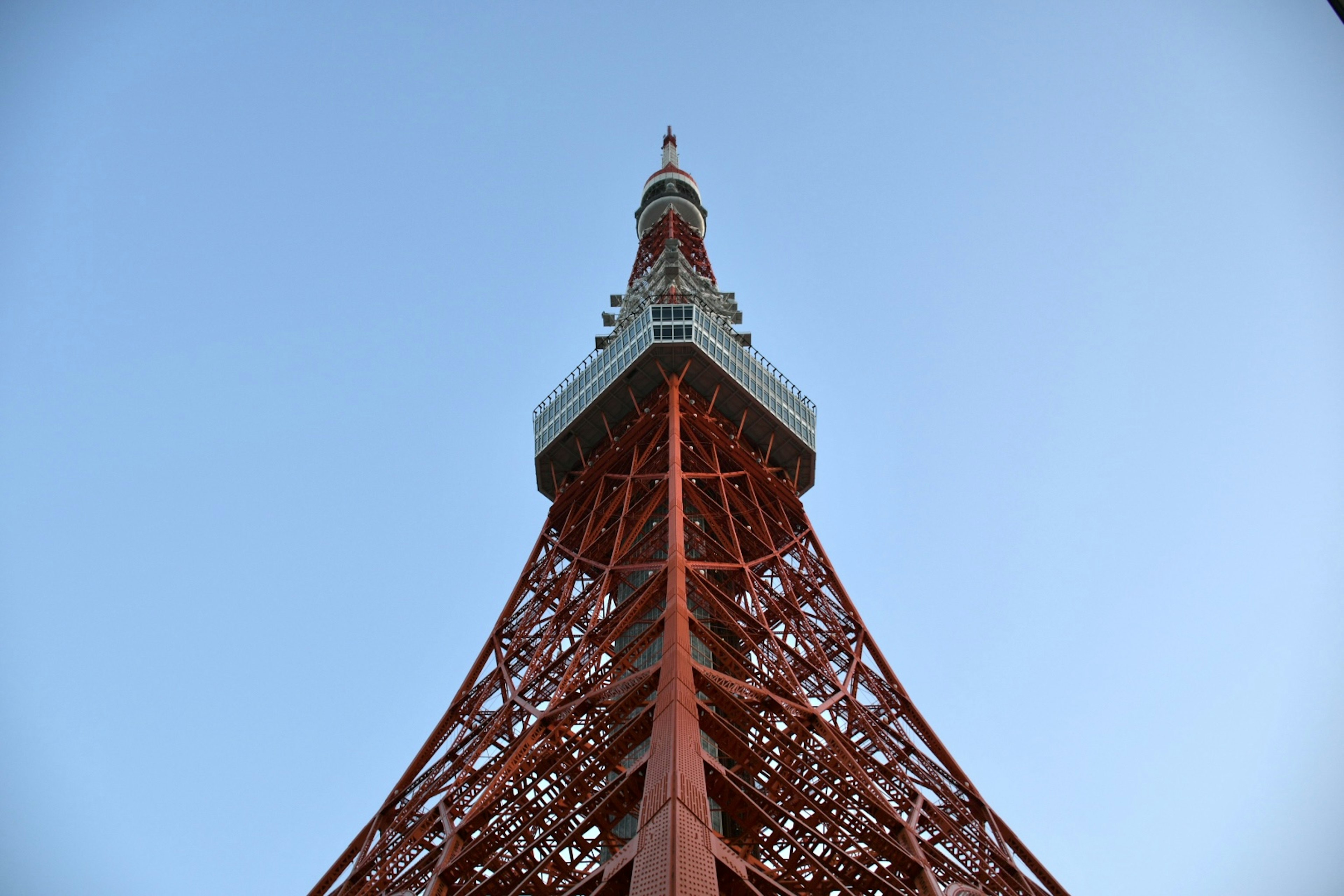 東京タワーの下から見上げた角度の写真青空の下にそびえる赤い鉄塔