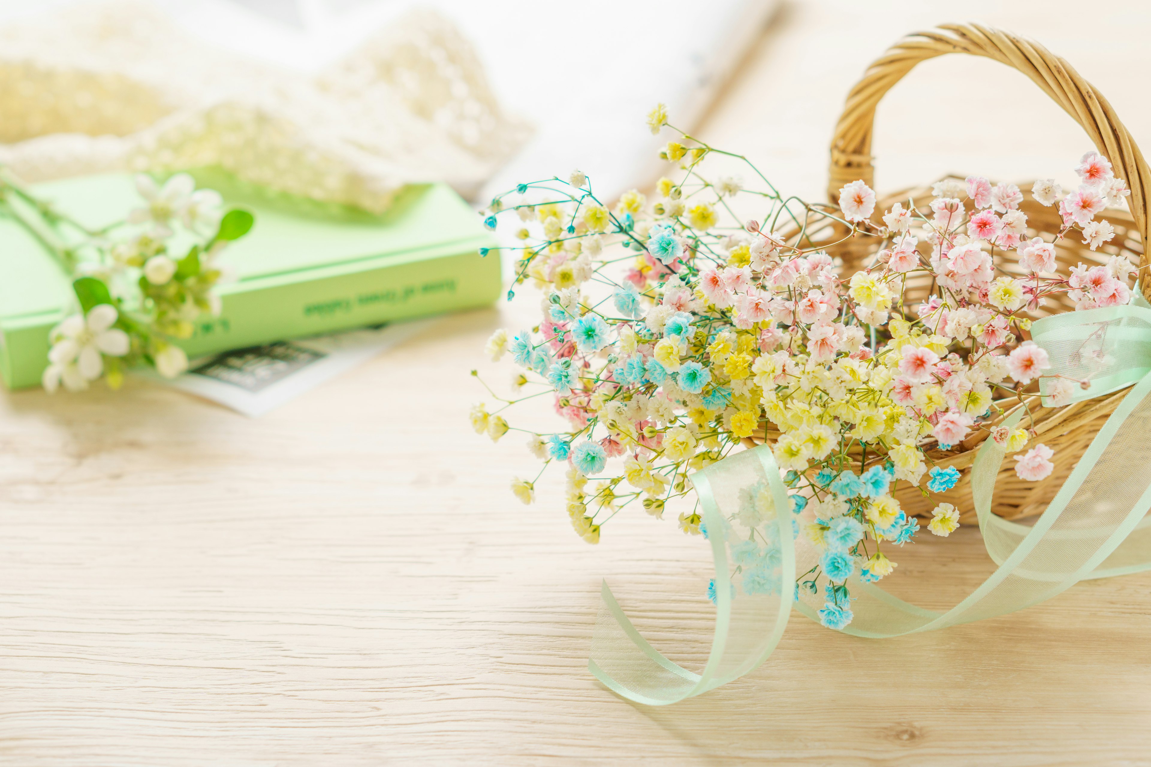 A basket filled with colorful flowers next to a green book