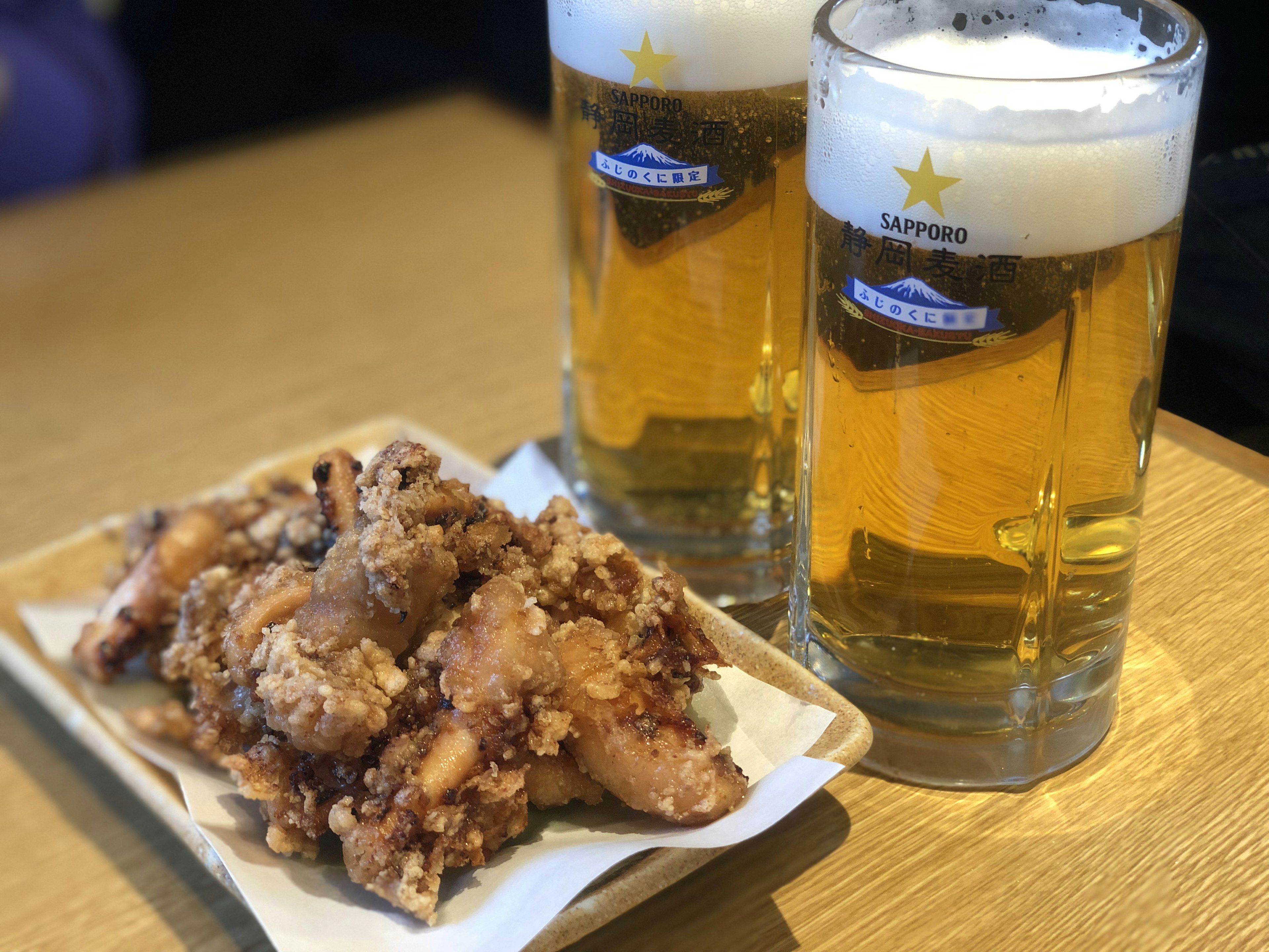 Bild von zwei Gläsern Bier und einem Teller mit frittiertem Hühnchen