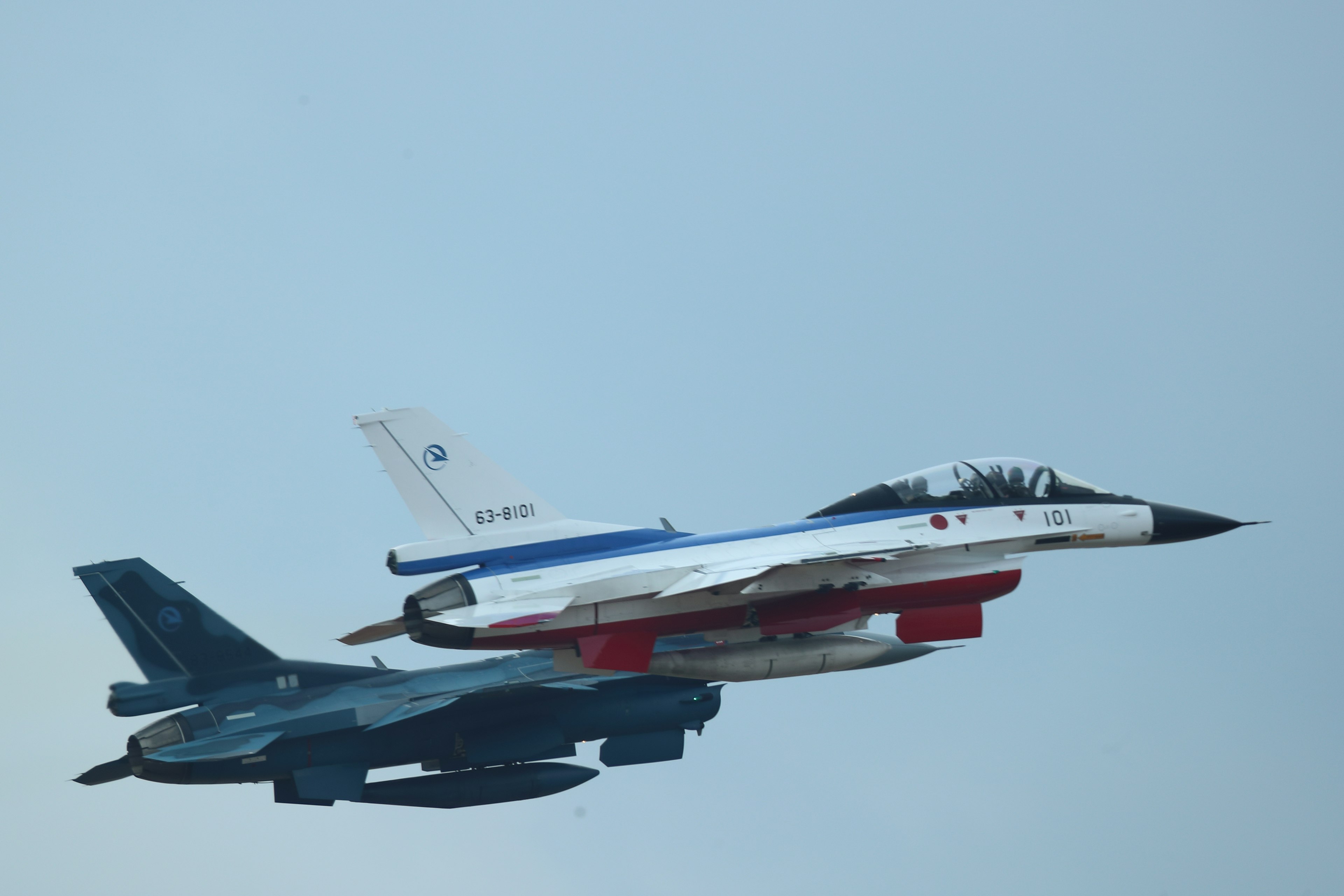 Zwei Jagdflugzeuge fliegen in Formation gegen einen klaren blauen Himmel