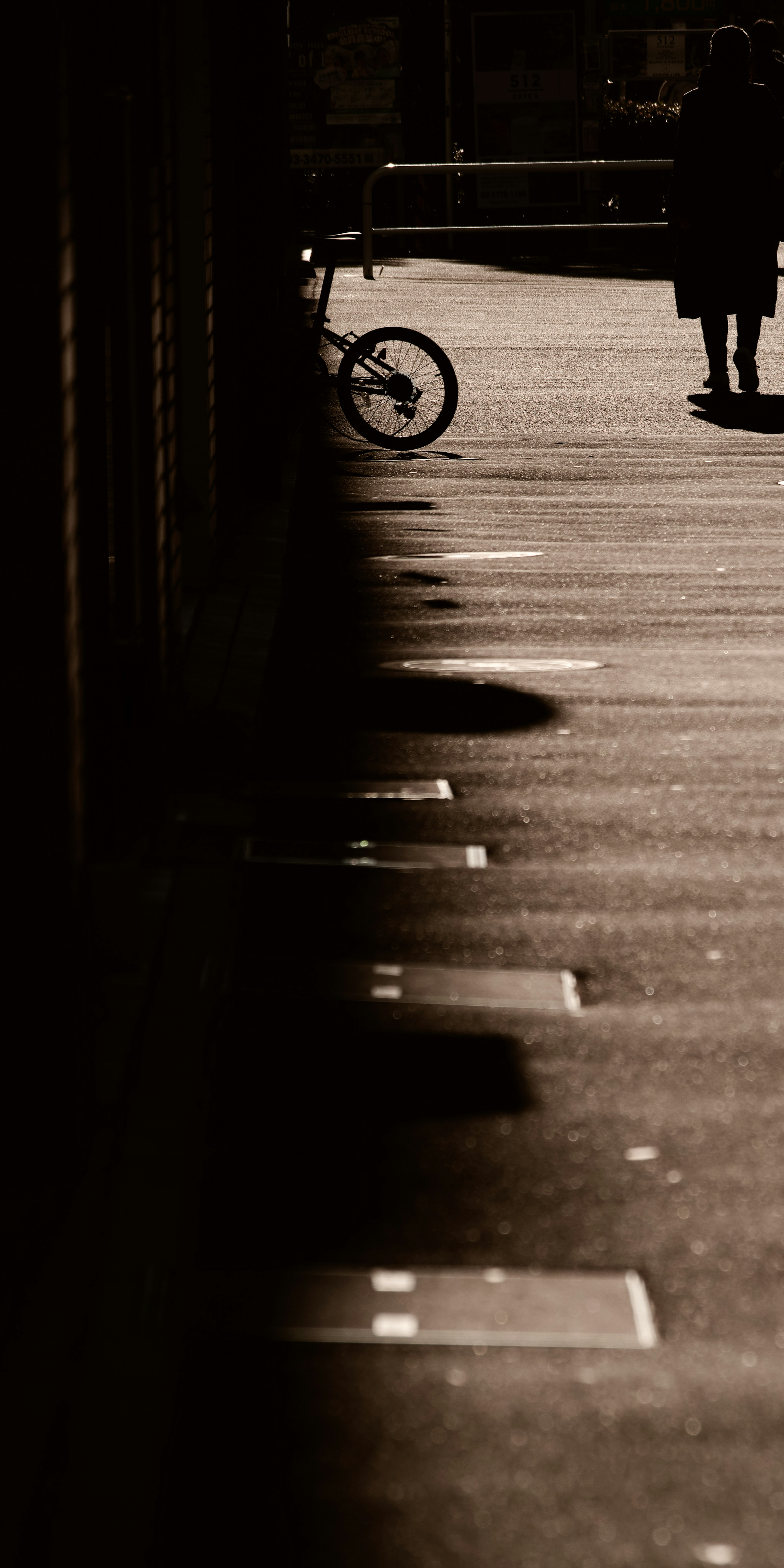 Eine schattige Straßenszene mit einem Fahrrad und der Silhouette einer Person