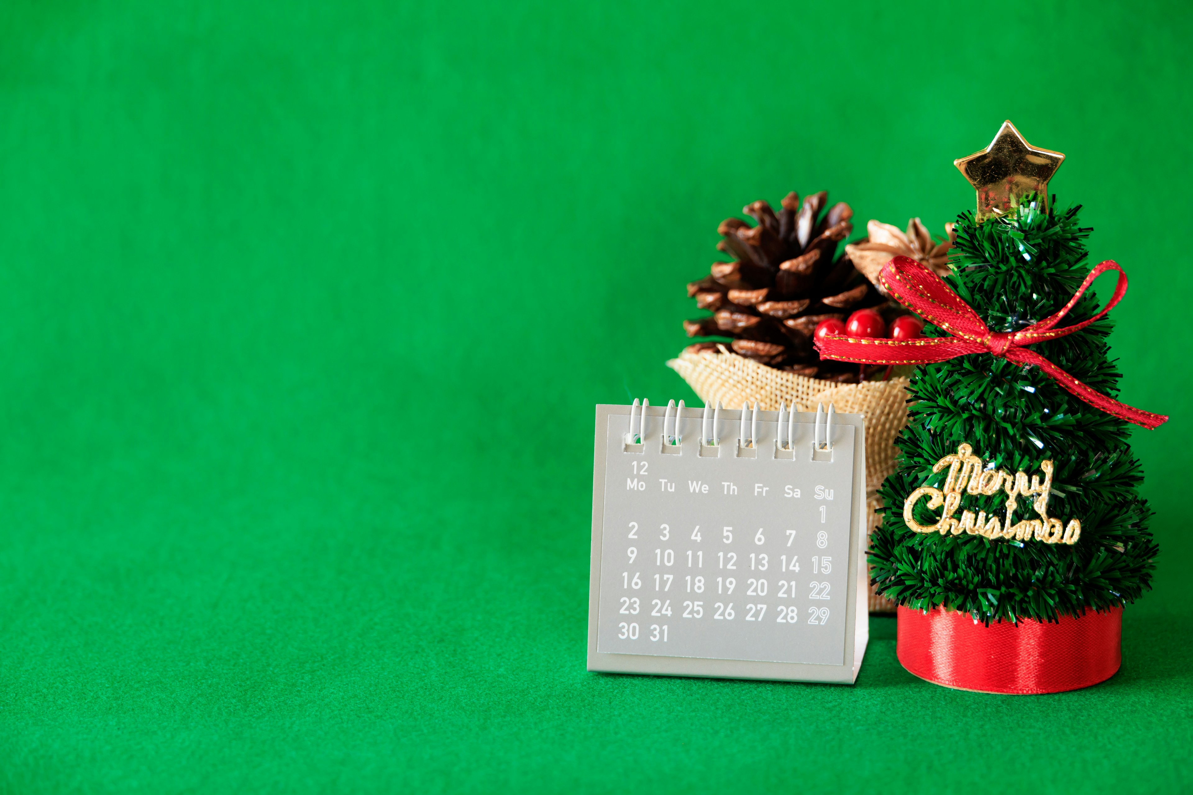 Pohon Natal kecil dan kalender di latar belakang hijau