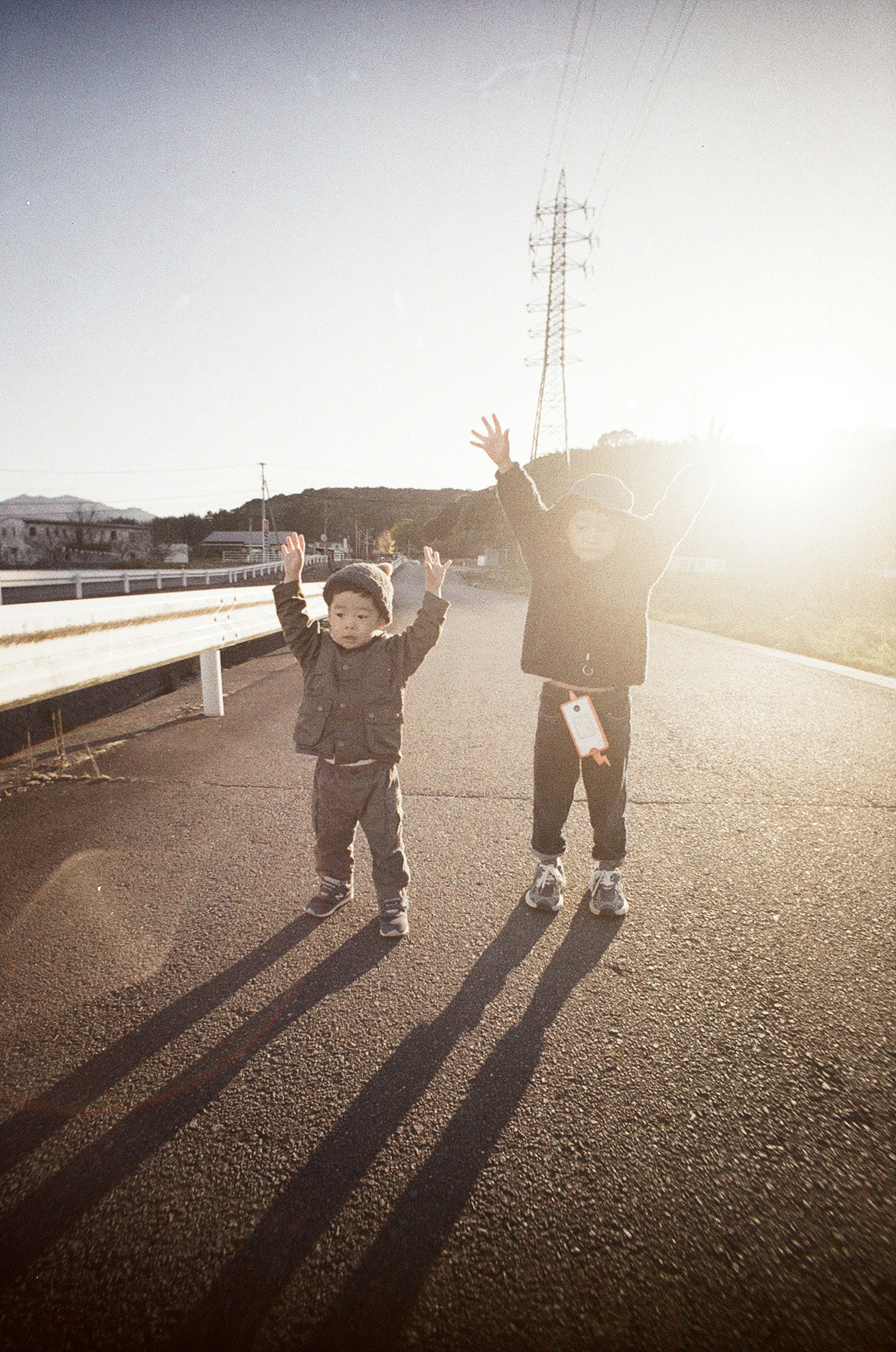 Silhouette of a child and adult raising their hands in sunlight