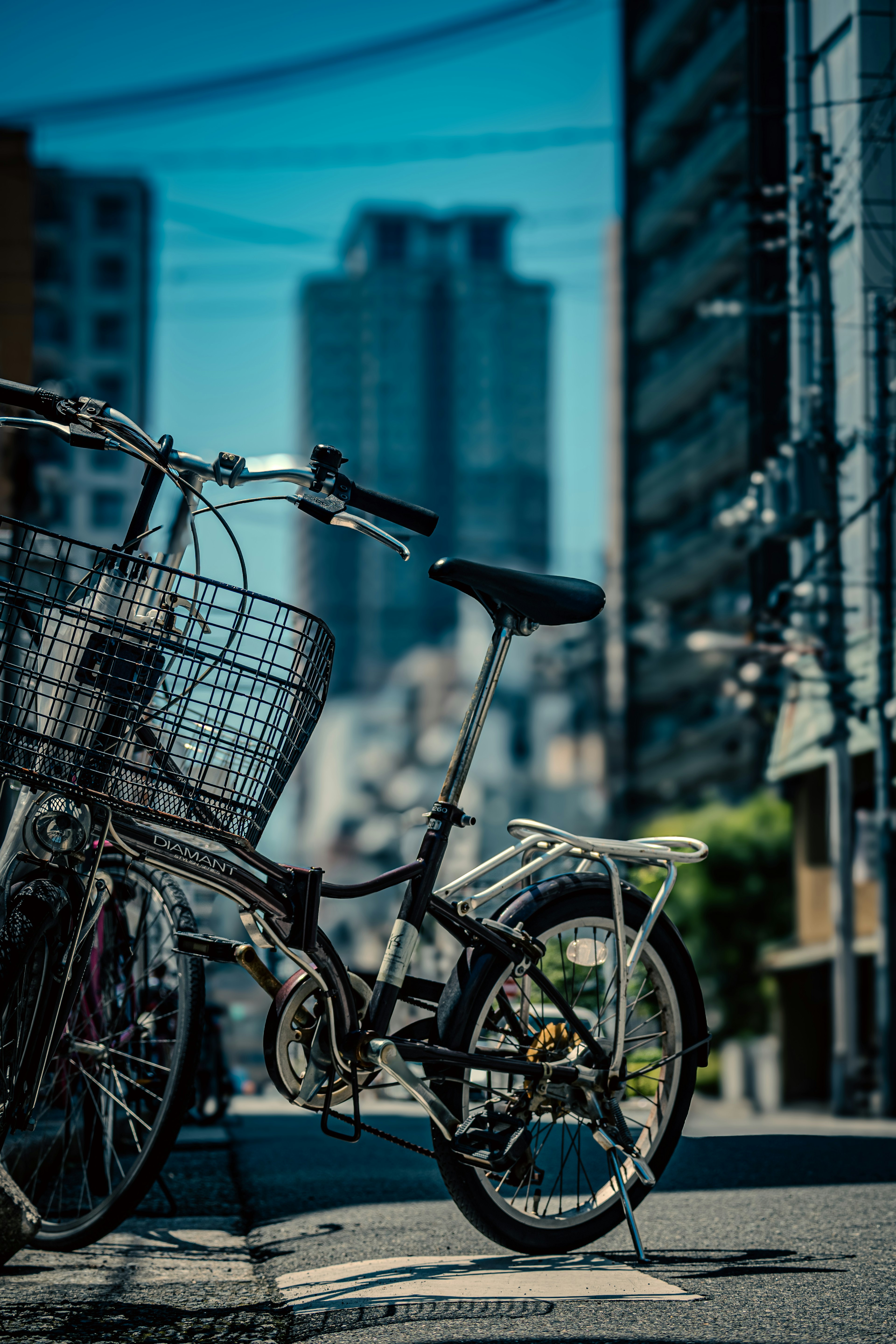 A bicycle parked in the street with skyscrapers in the background