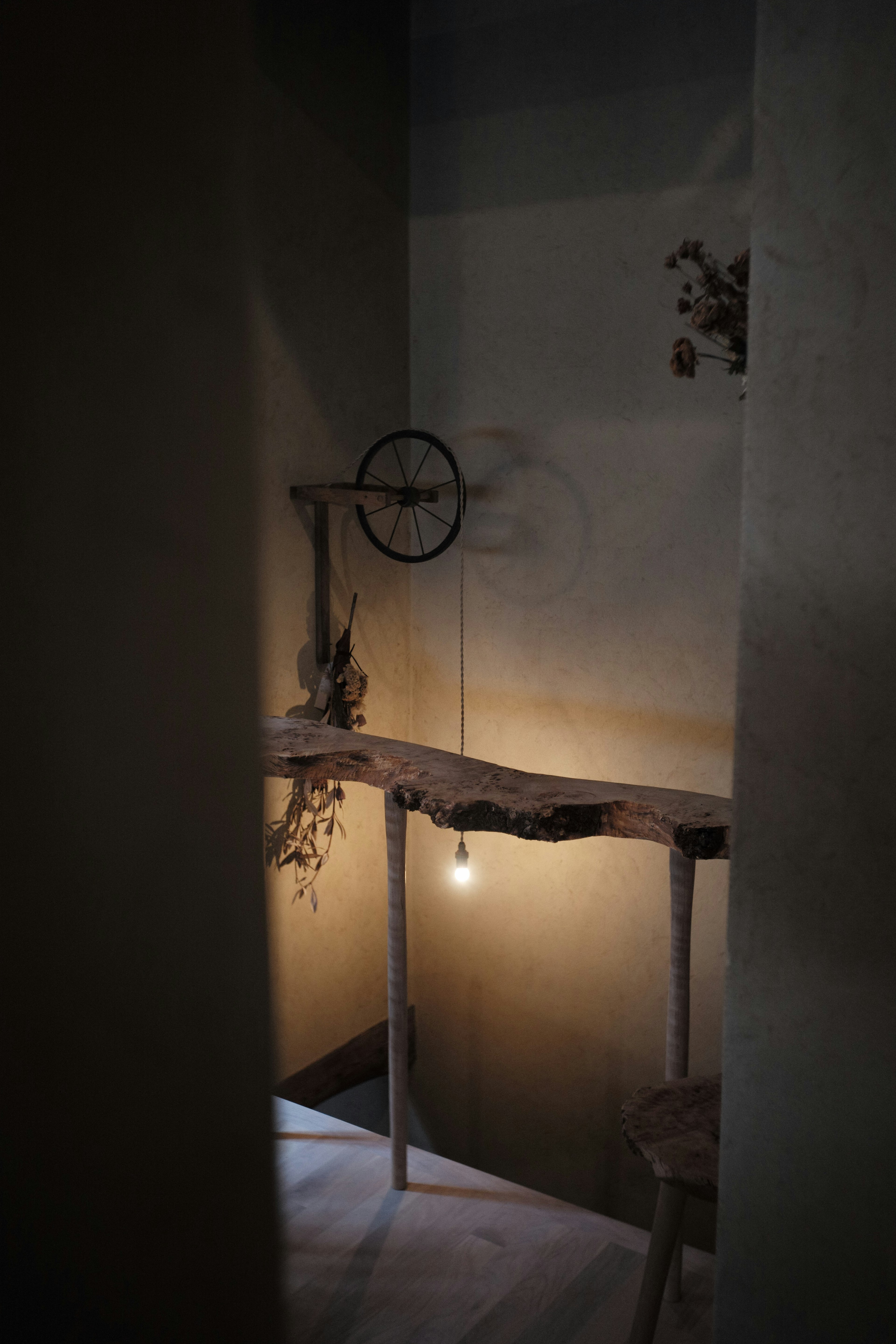 Dimly lit space with wooden shelf and hanging light bulb