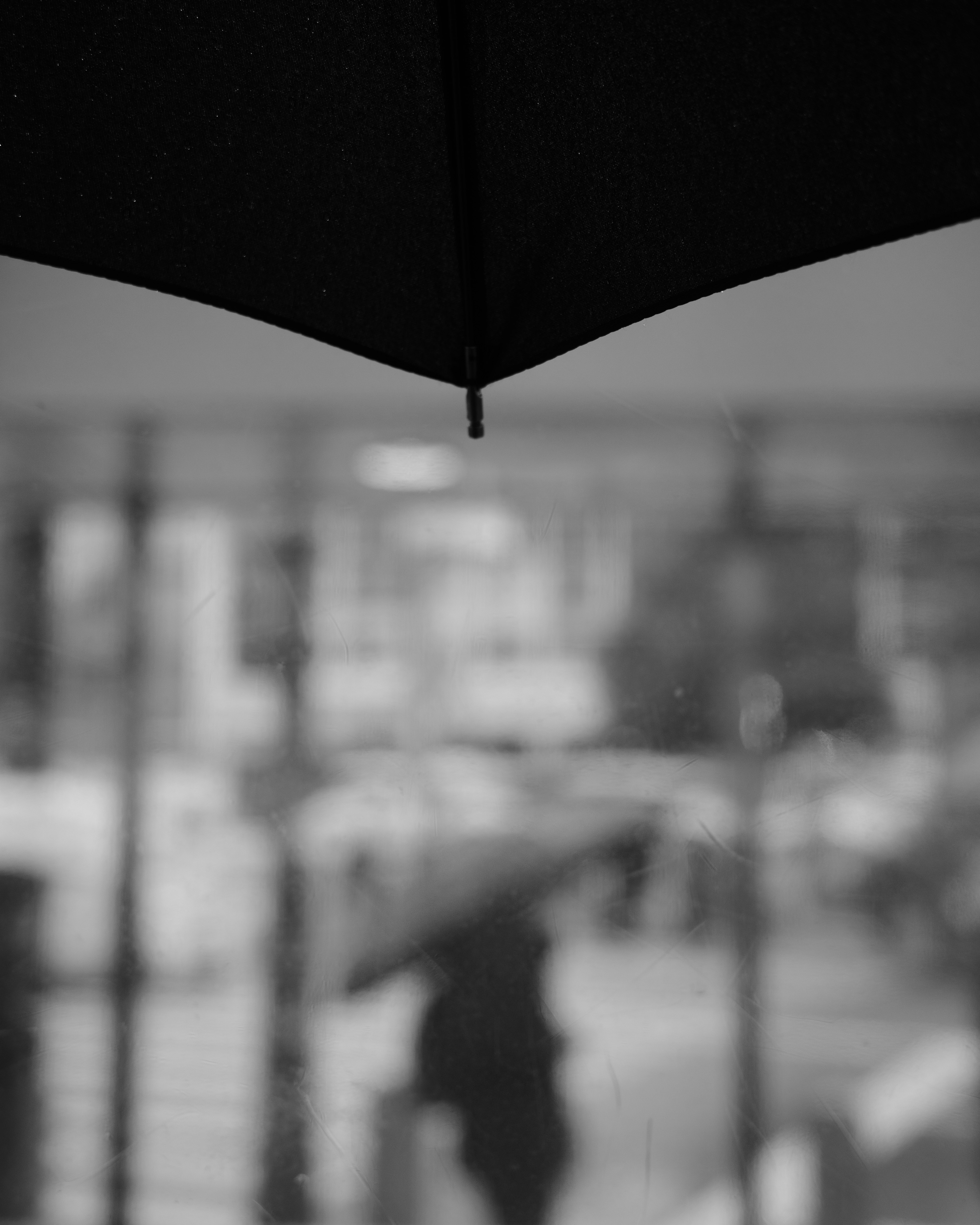 Silhouette of a person under an umbrella with a blurred city background