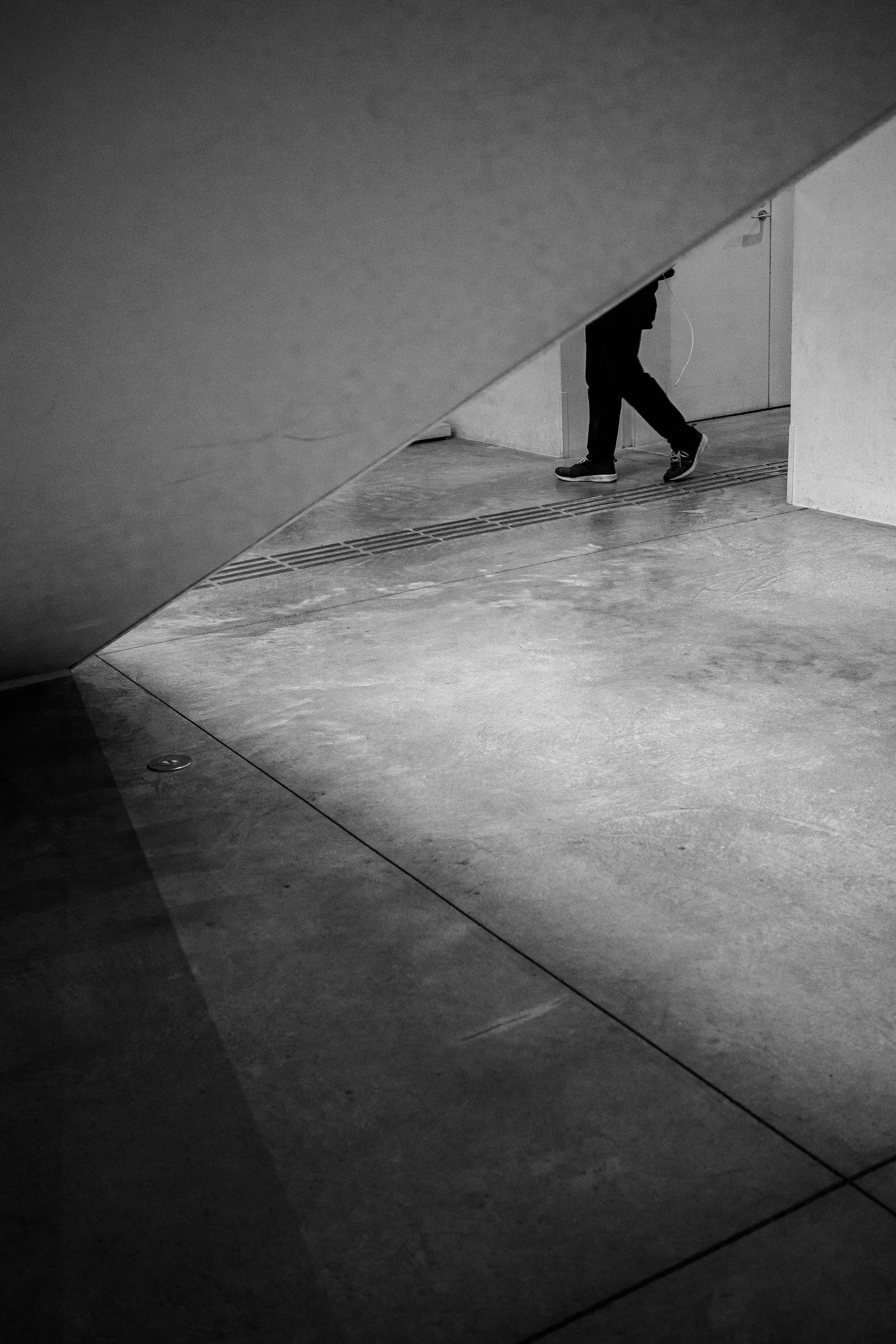 Une personne marchant dans un espace en noir et blanc avec un angle mural diagonal