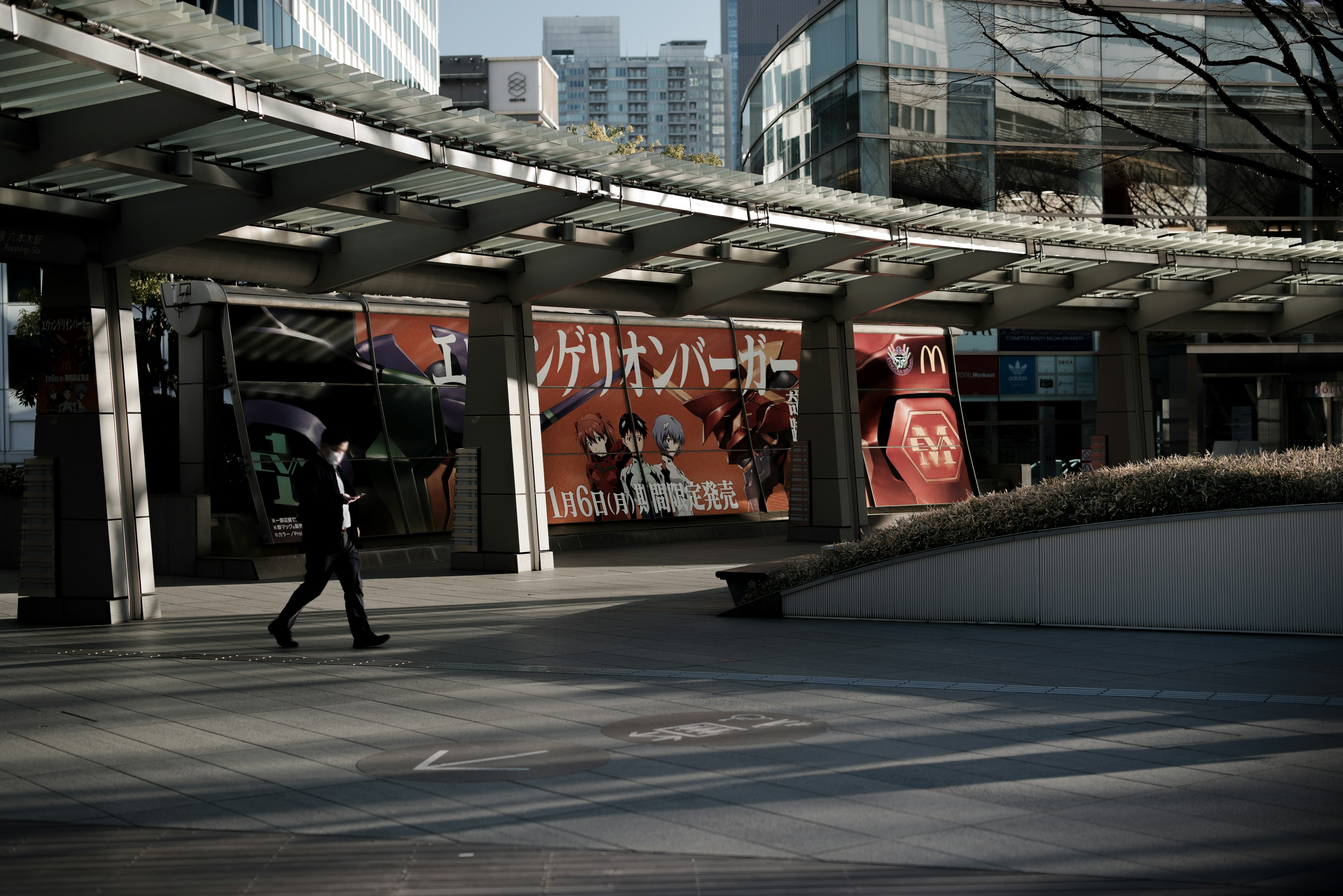 一个人在城市广场上走，背景是麦当劳的横幅和现代建筑