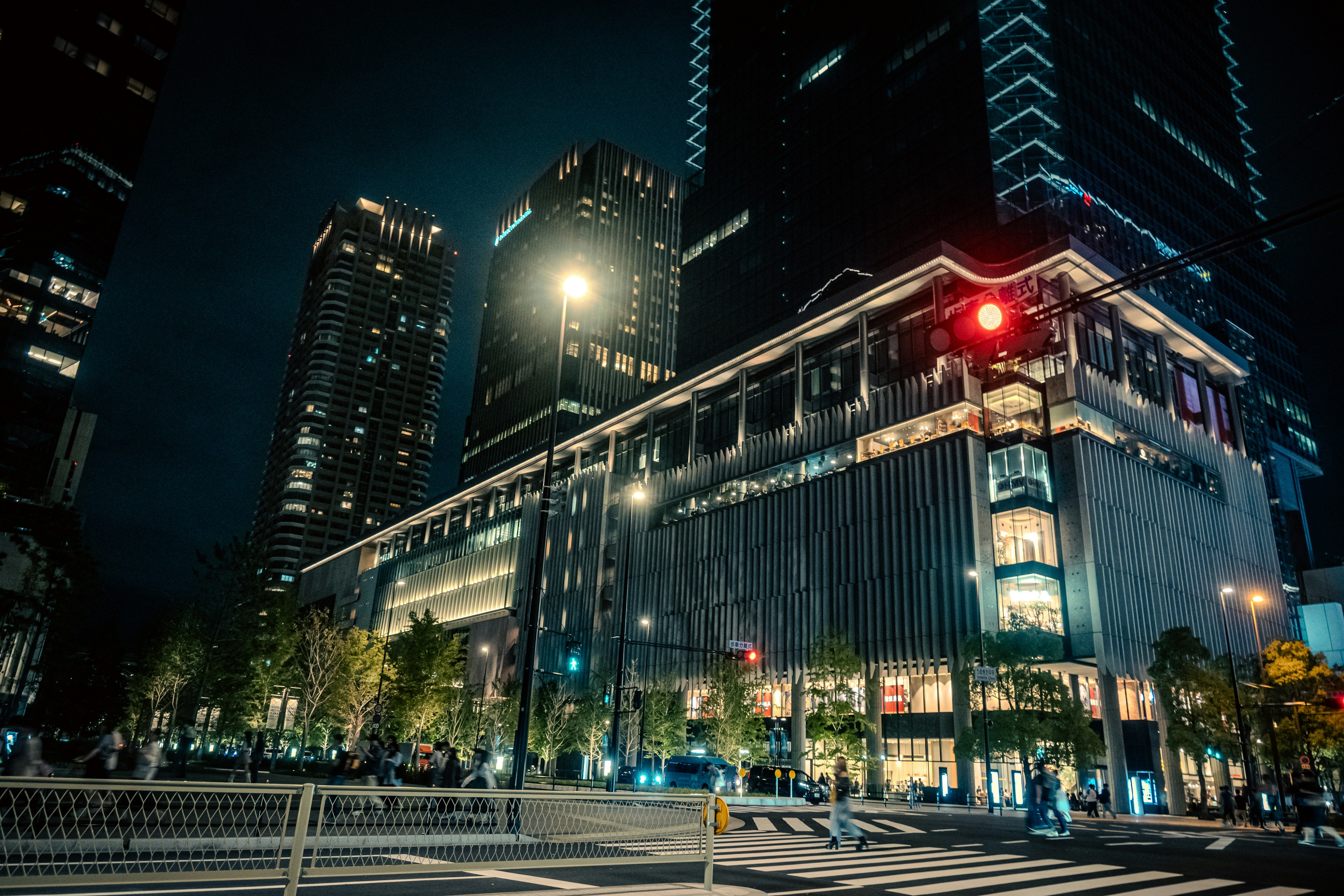 Urban night scene featuring towering skyscrapers and a bright traffic light